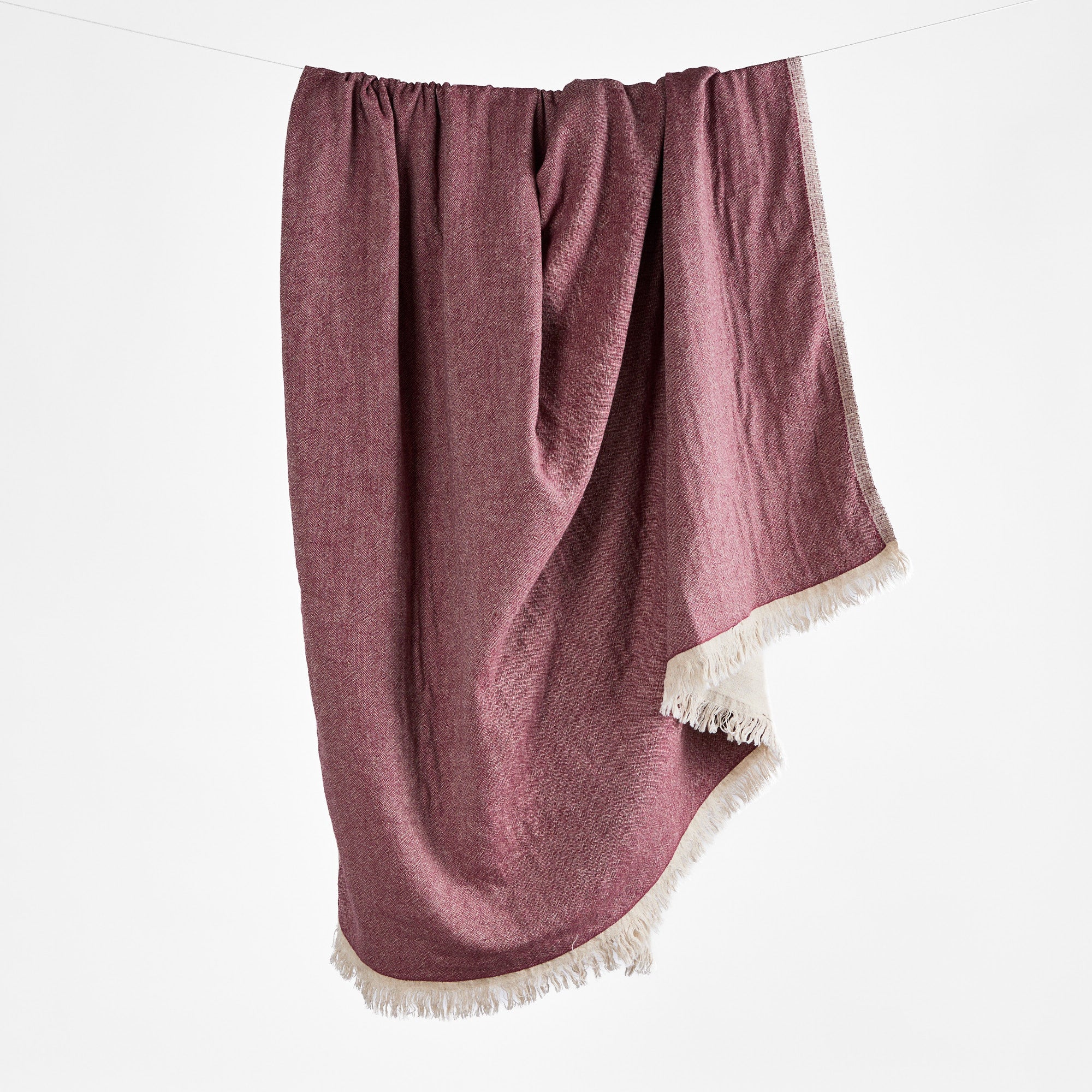 Alba Cranberry red linen-cotton throw blanket draped for a cozy layered look – Tonic Living