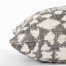 a black and cream abstract floral patterned lumbar throw pillow : close up side view