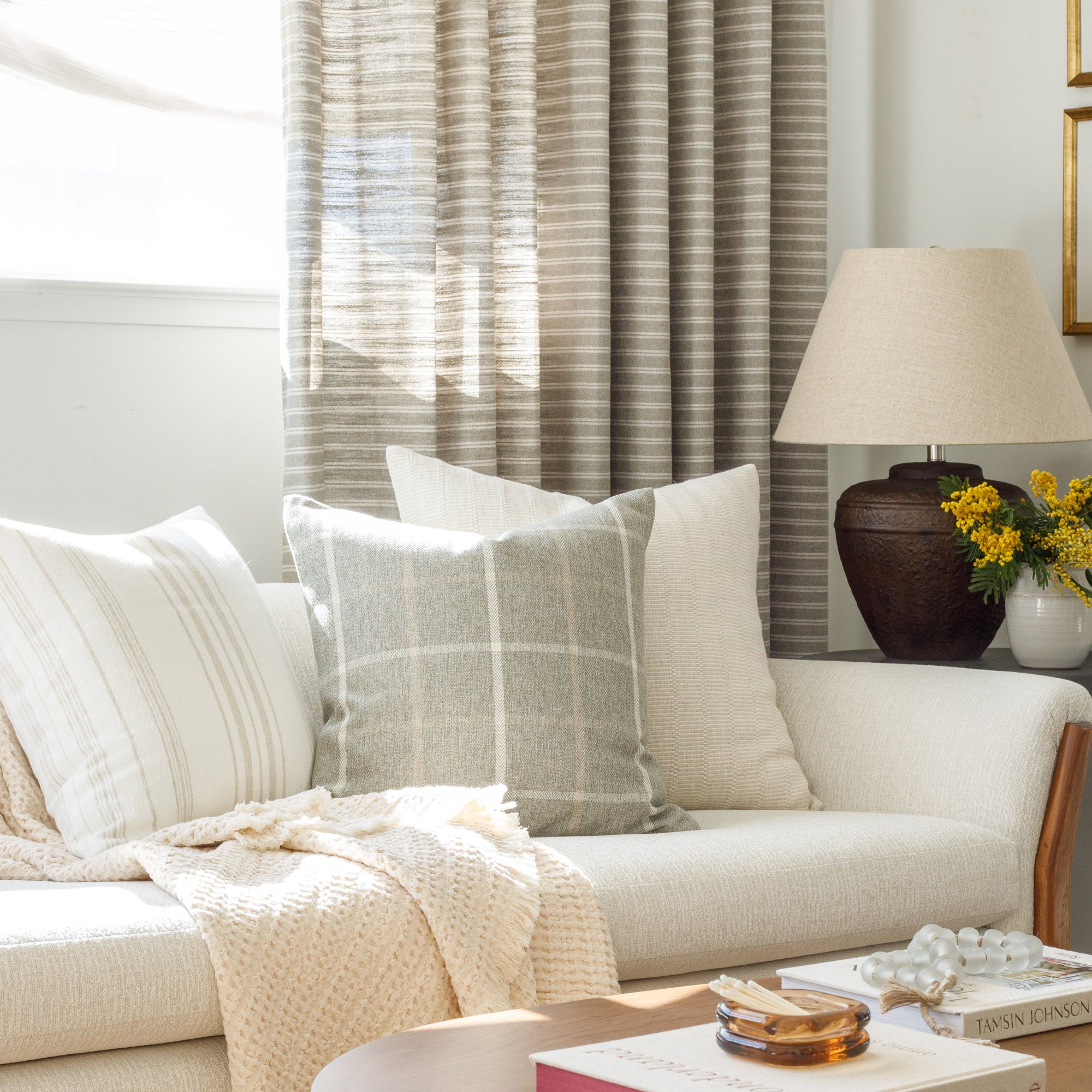 A selection of neutral throw pillows from Tonic Living, styled on a sofa.