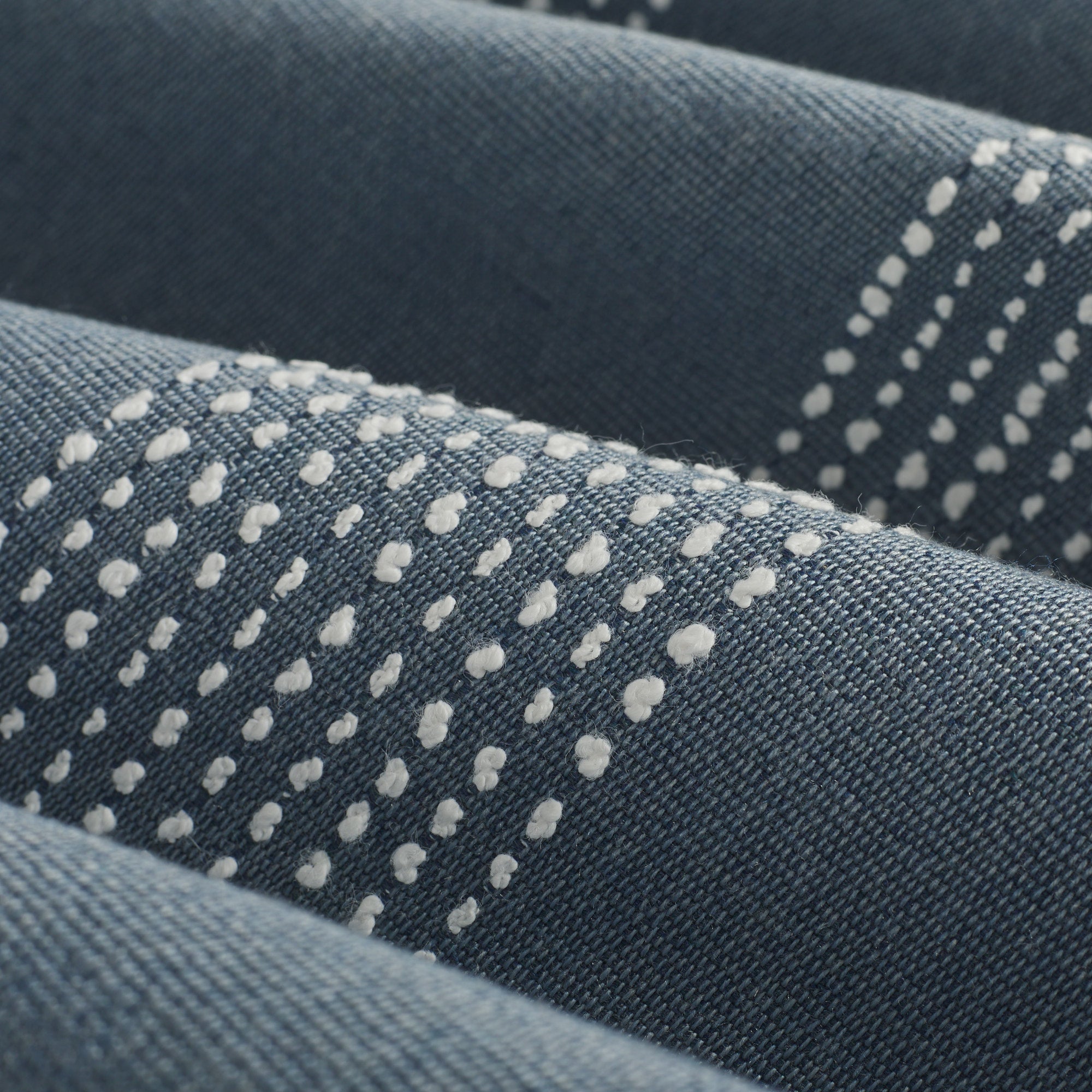 Close up of Tonic Living Caper Sunbrella Slate fabric showing raised stitched stripe detail in slate blue and white.