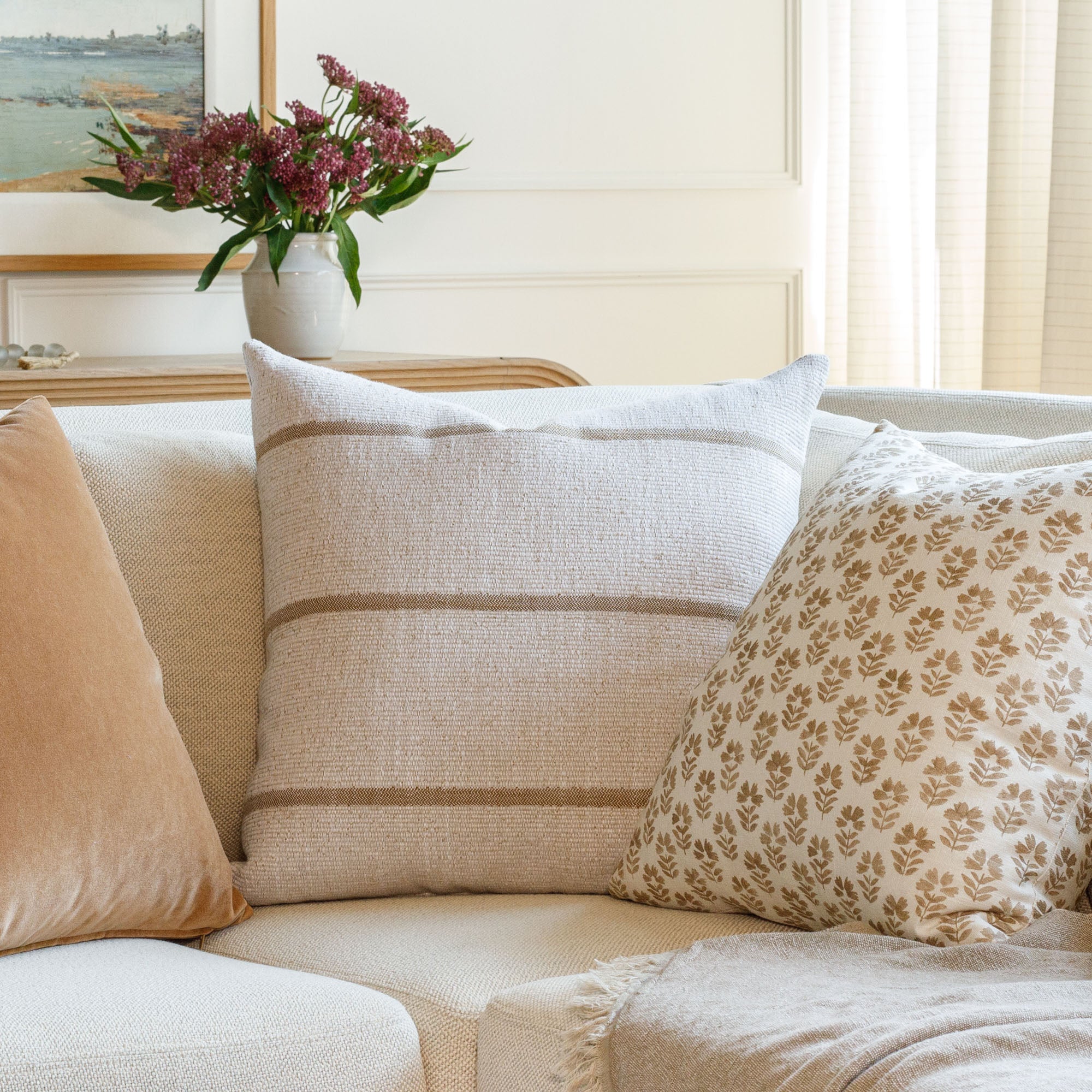 A group of neutral throw pillows from Tonic Living, styled on a sofa.