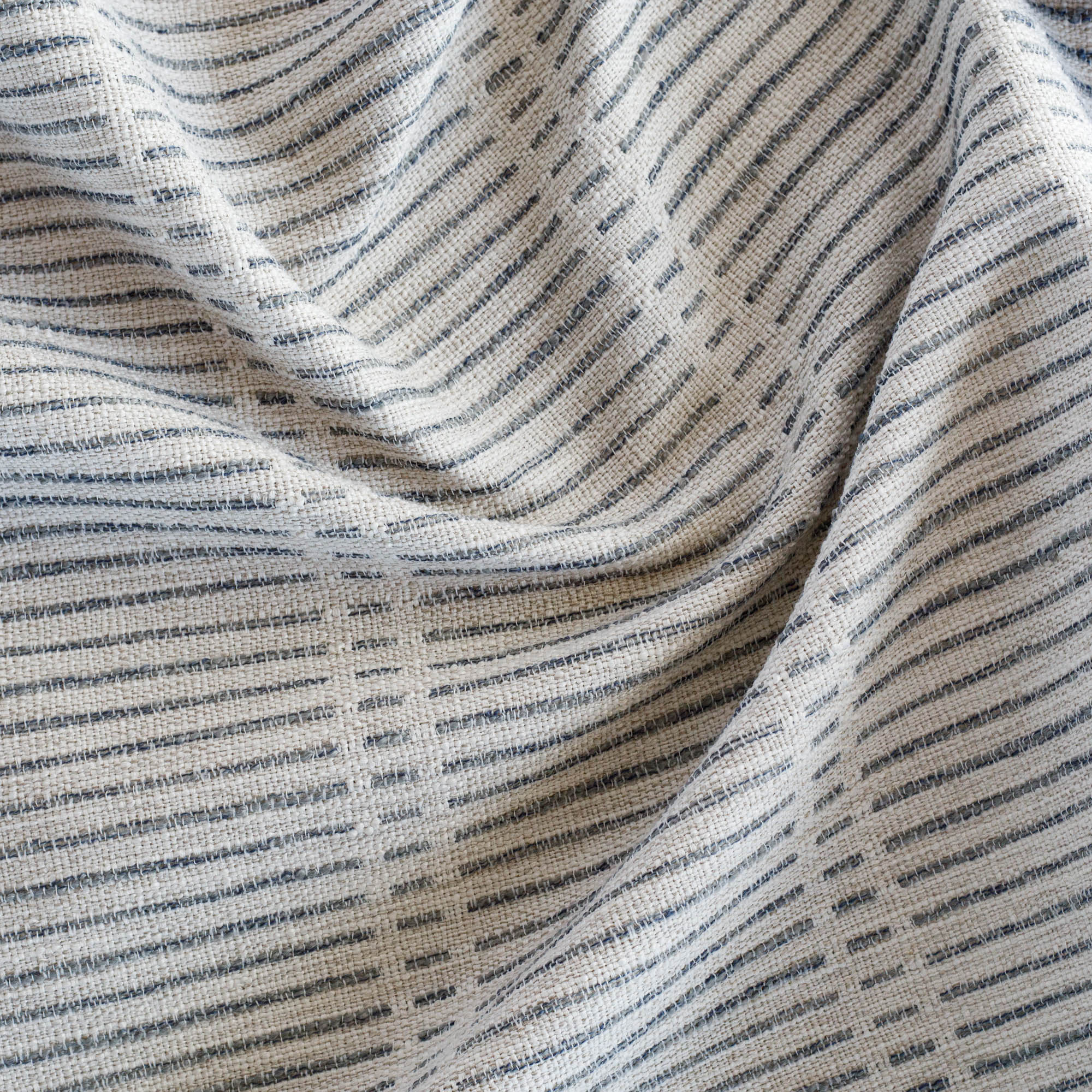 a woven light beige and blue dashed stripe patterned home decor fabric