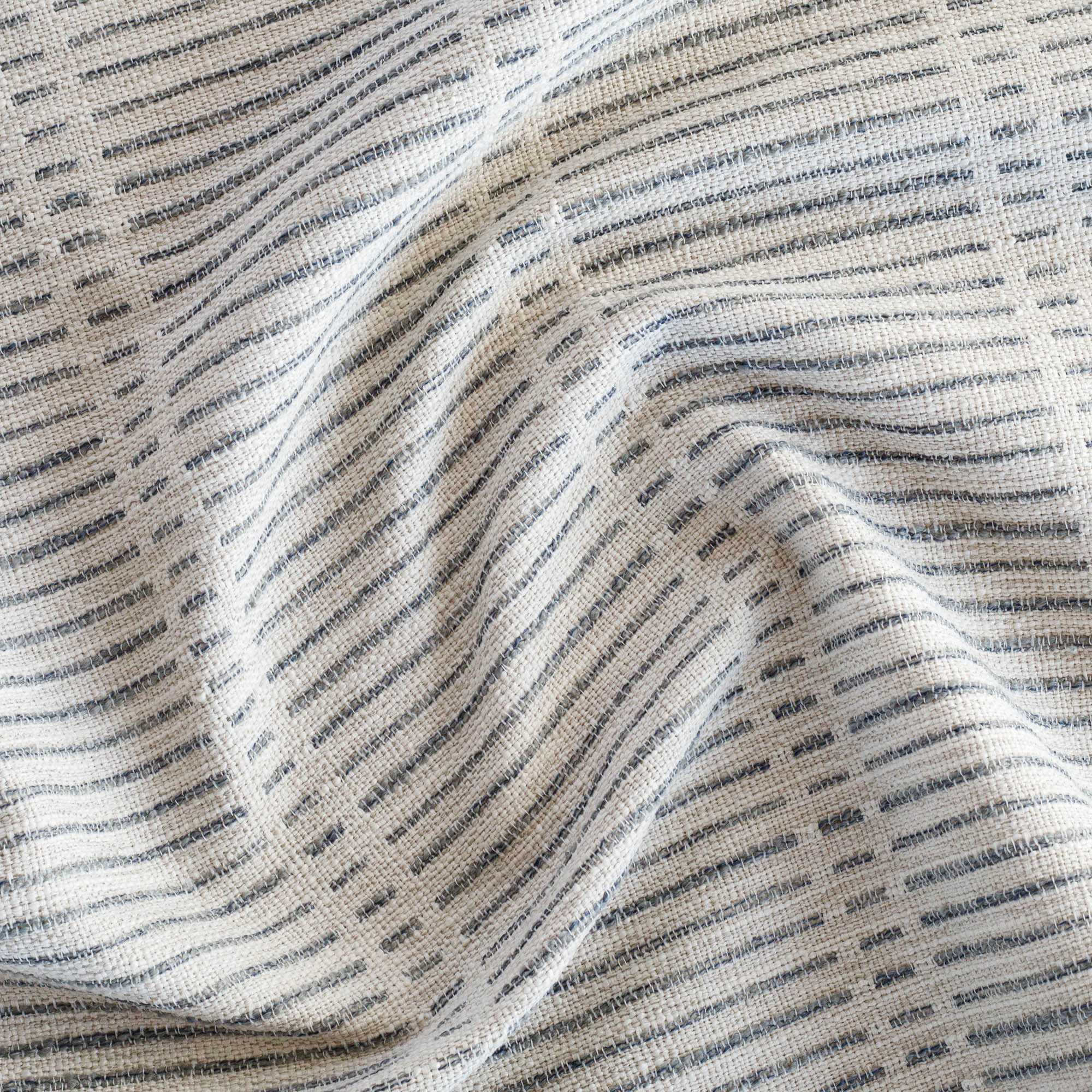 a woven light beige and blue dashed stripe patterned upholstery fabric : close up view