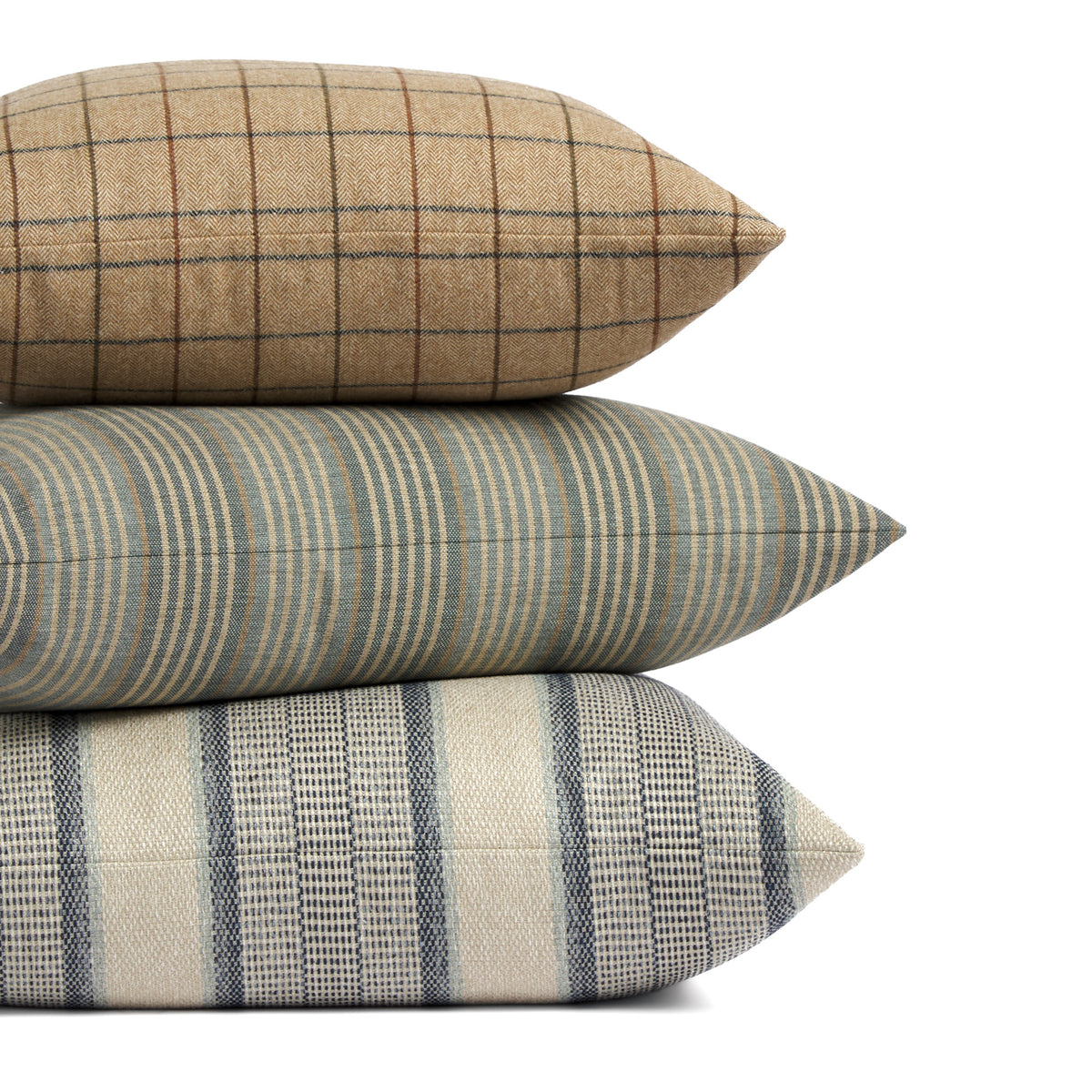 Stack of Tonic Living pillows featuring Walker Plaid, Clark Stripe, and Miller Stripe in coordinating blue, brown, and neutral tones.