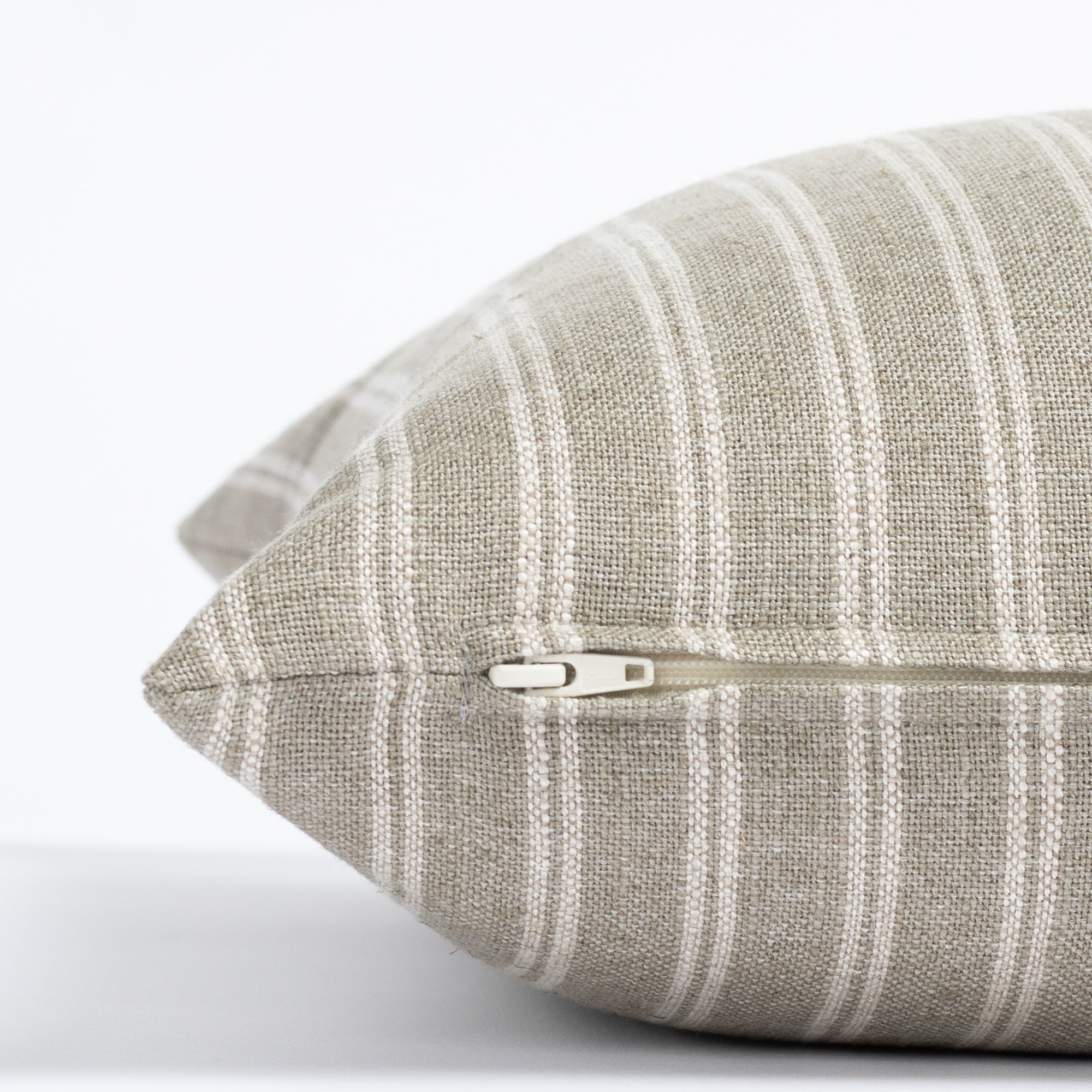 a dusty sage green and oatmeal beige vertical stripe throw pillow : close up zipper view