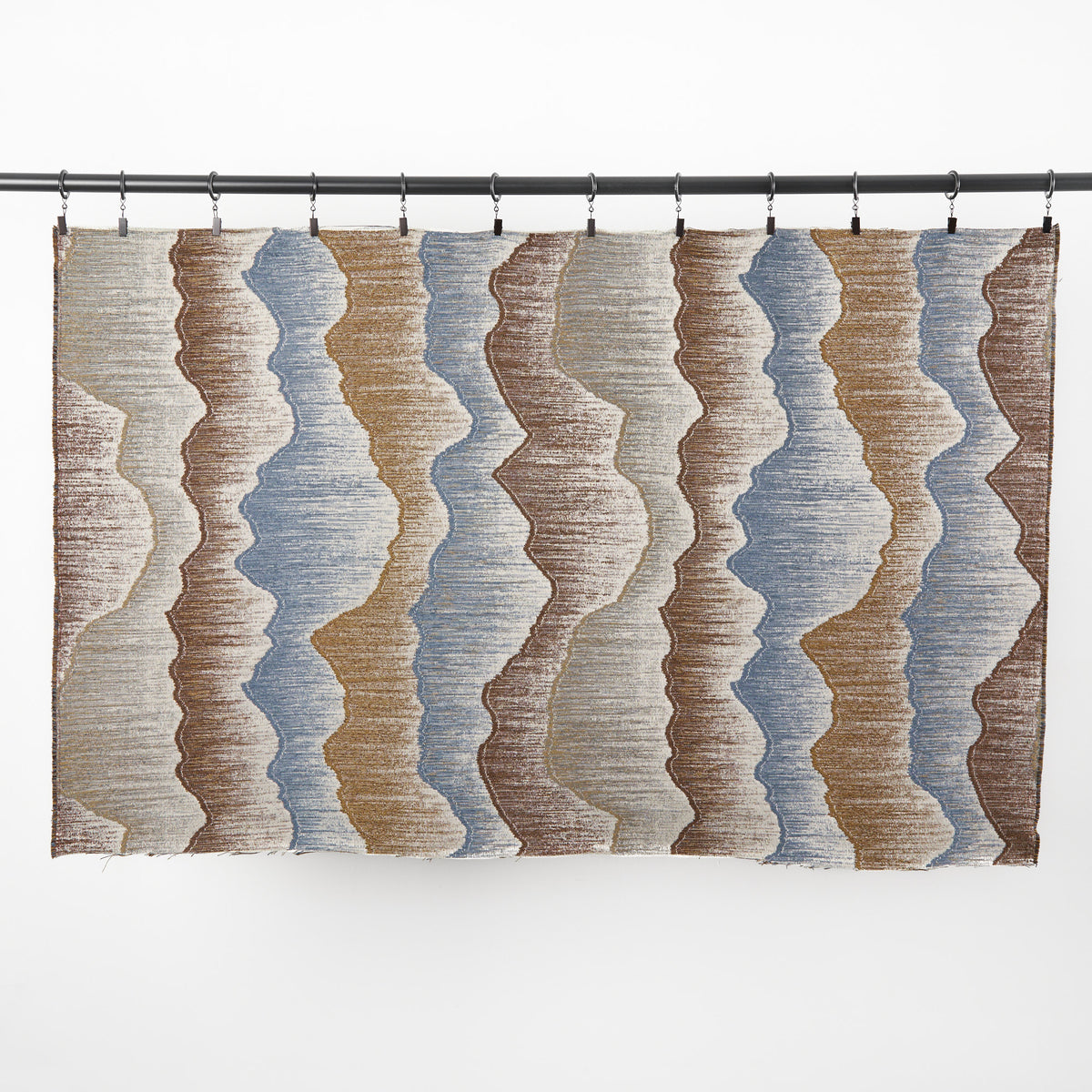 Full yard of Tonic Living Cortina Fabric in Storm hanging to show the scale of its blue and brown organic abstract pattern.