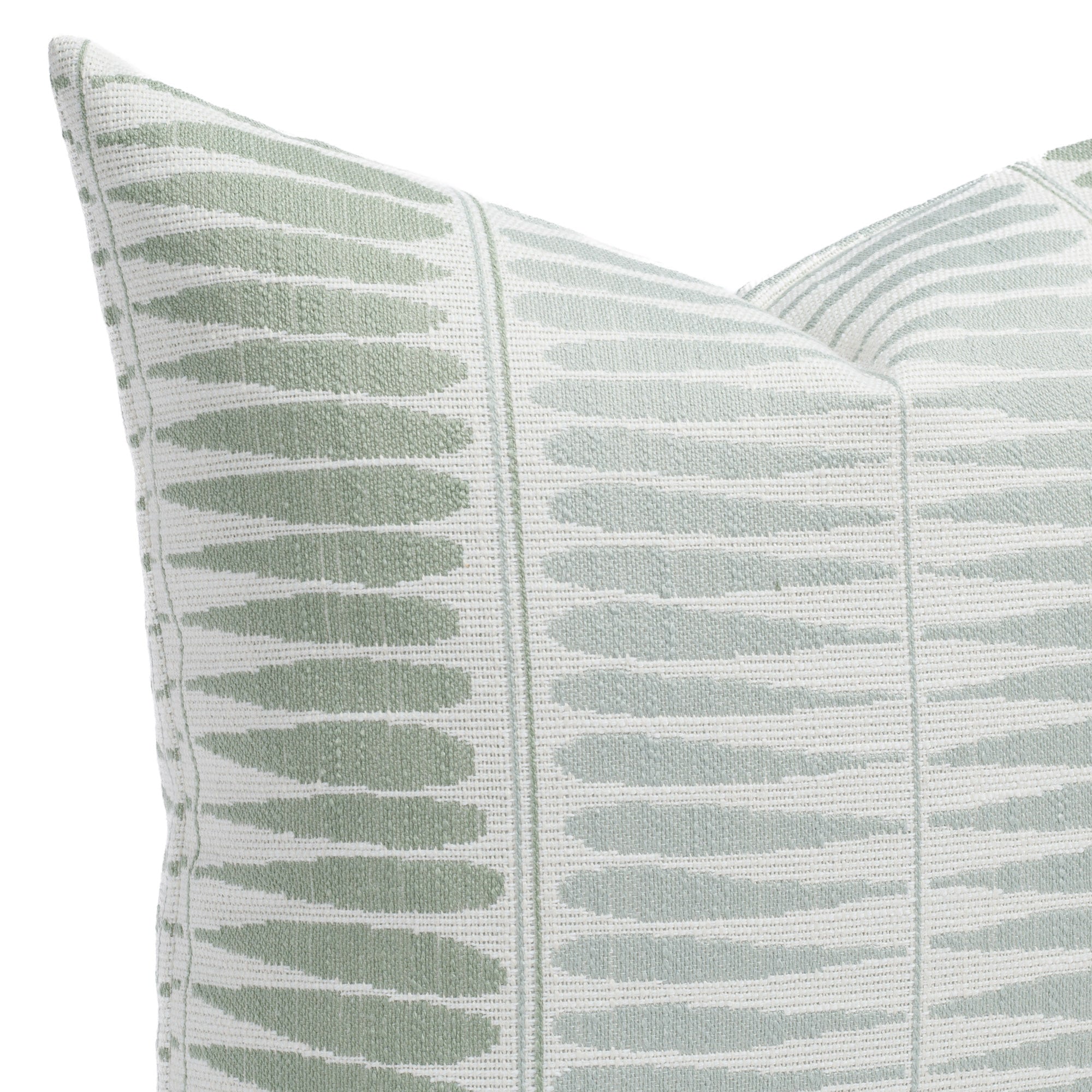 Everly Jade, an indoor/outdoor pillow in pale sage, dusty aqua, and soft white, featuring a pattern of elongated teardrop shapes: close-up view.