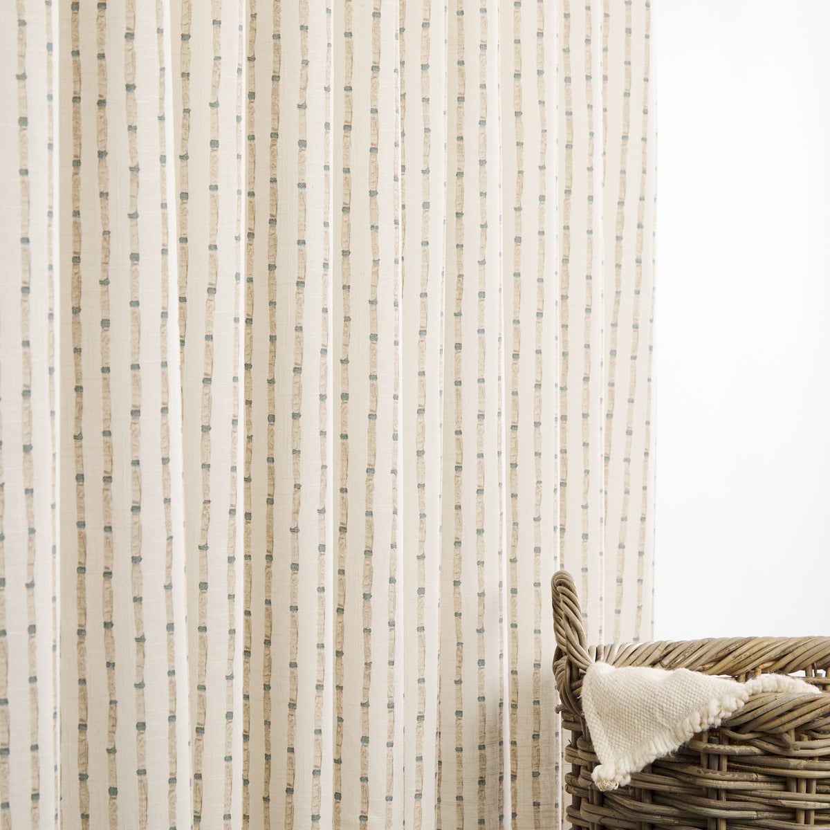 Tonic Living Hadley Stripe drapery fabric shown as striped curtains featuring blue and light brown bamboo-inspired detailing on an off-white ground.
