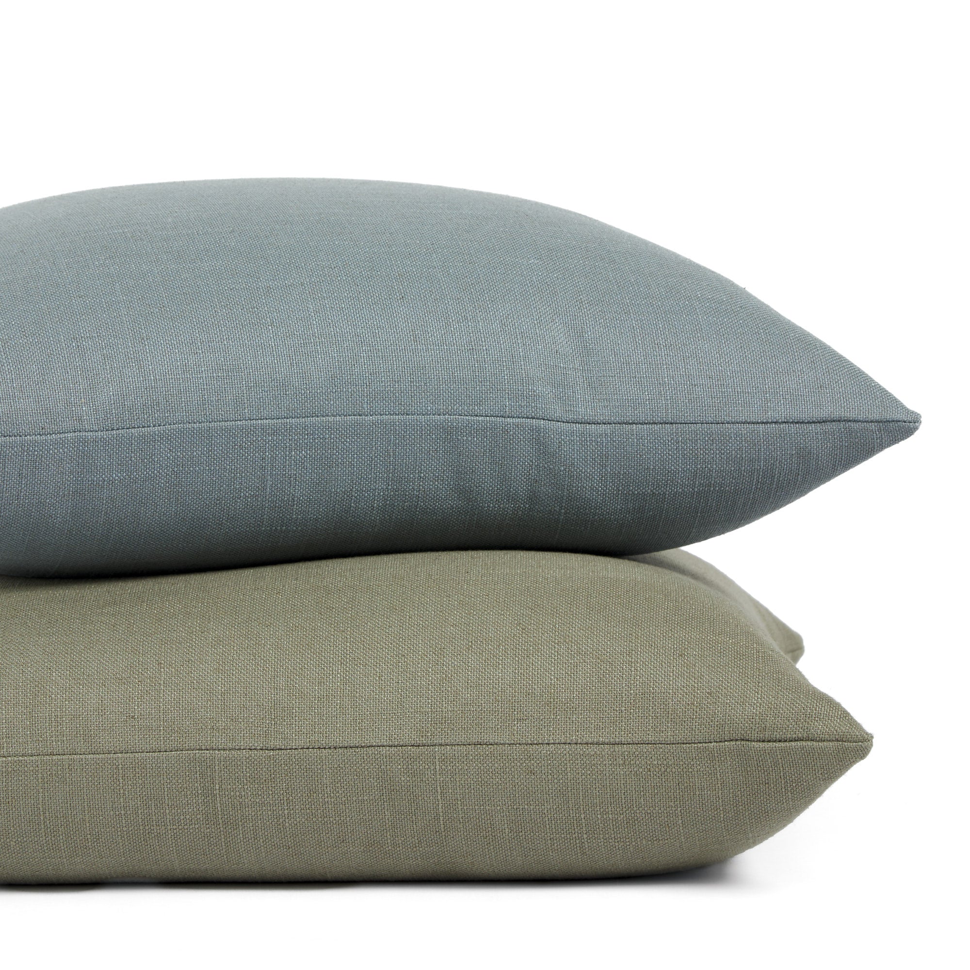 Stack of Tonic Living Hampton 24x24 pillows in Sage and Chambray featuring soft linen-look texture.