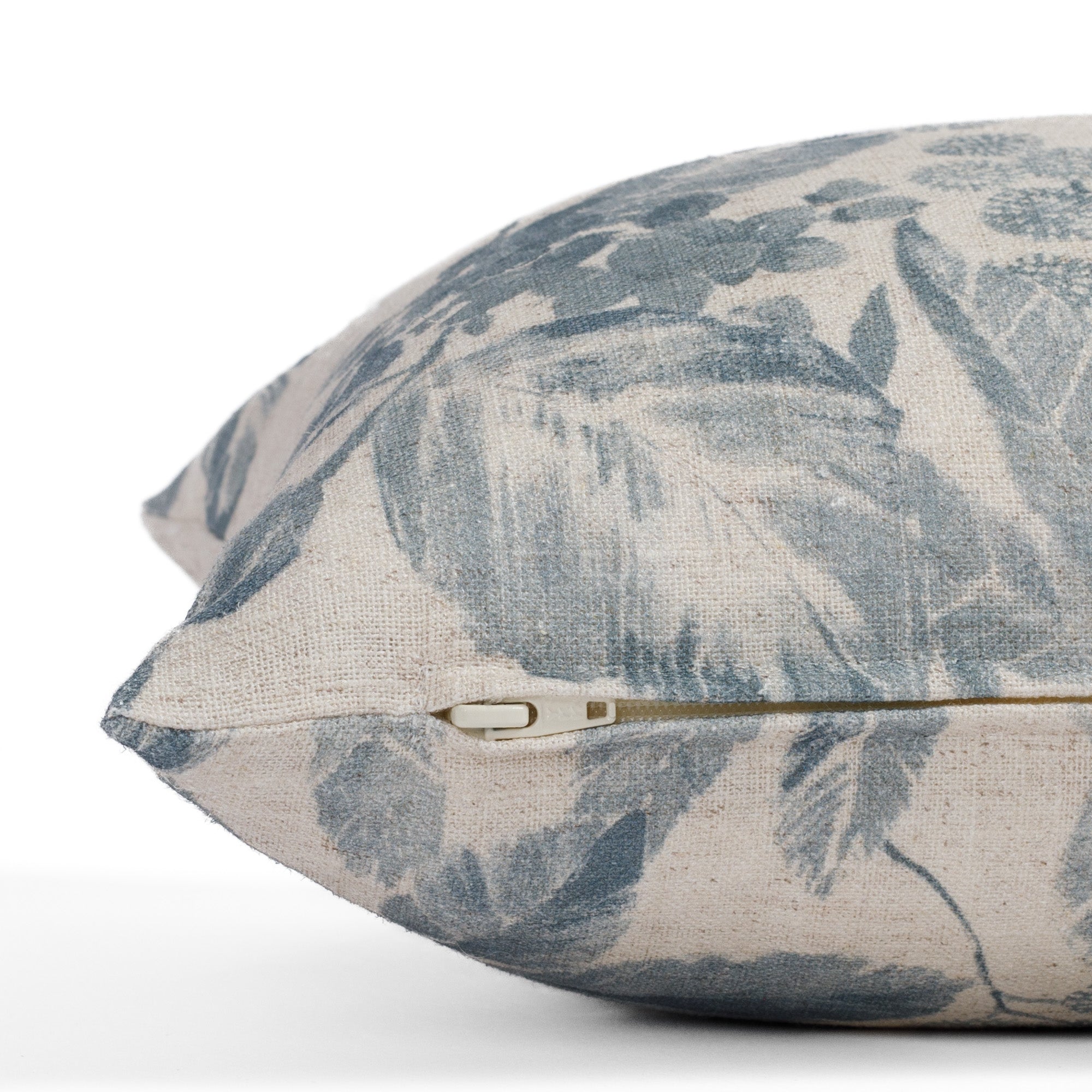 Side view of the Heather Indigo lumbar cushion by Tonic Living, showing the pillow’s zipper detail and a detailed look at the slubby fabric in washed indigo blue tones.