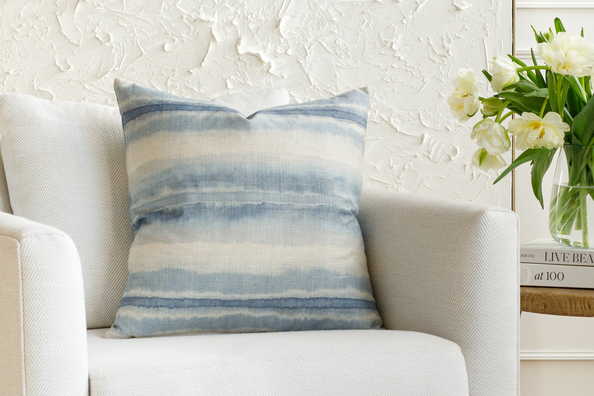 A blue and white pillow, styled on furniture.