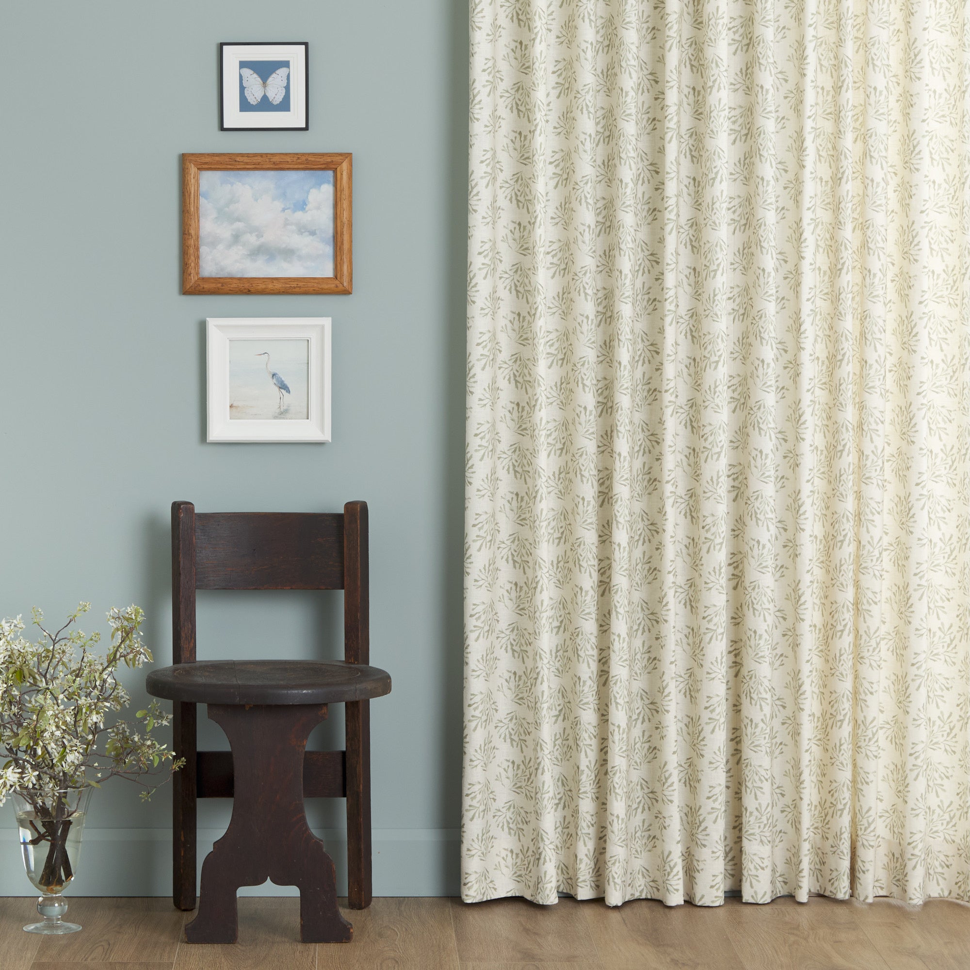 Tonic Living Juniper Sage curtain fabric shown as full drapery in a blue room with classic decor.