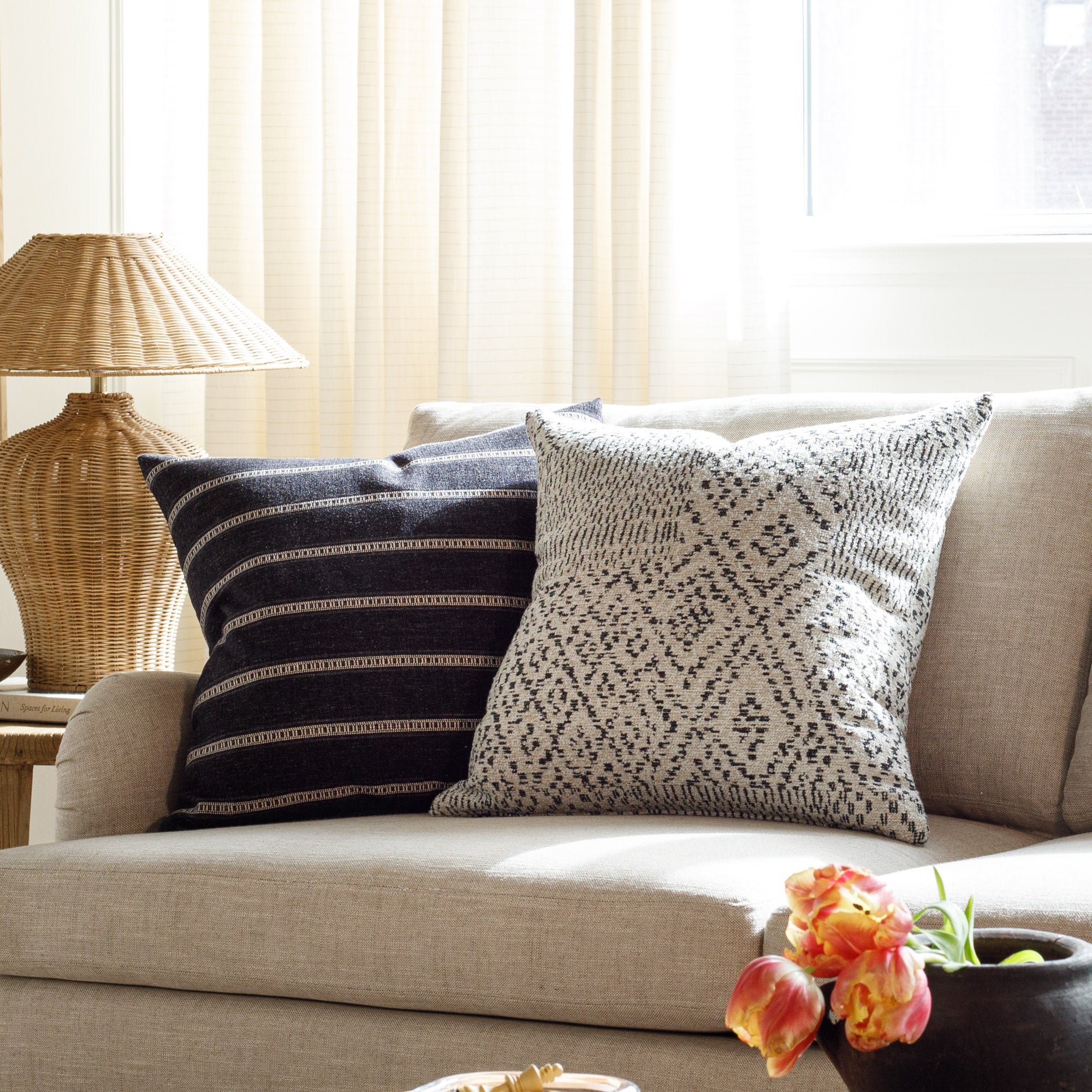 Black and neutral patterned designer pillows from Tonic Living, styled on a couch.