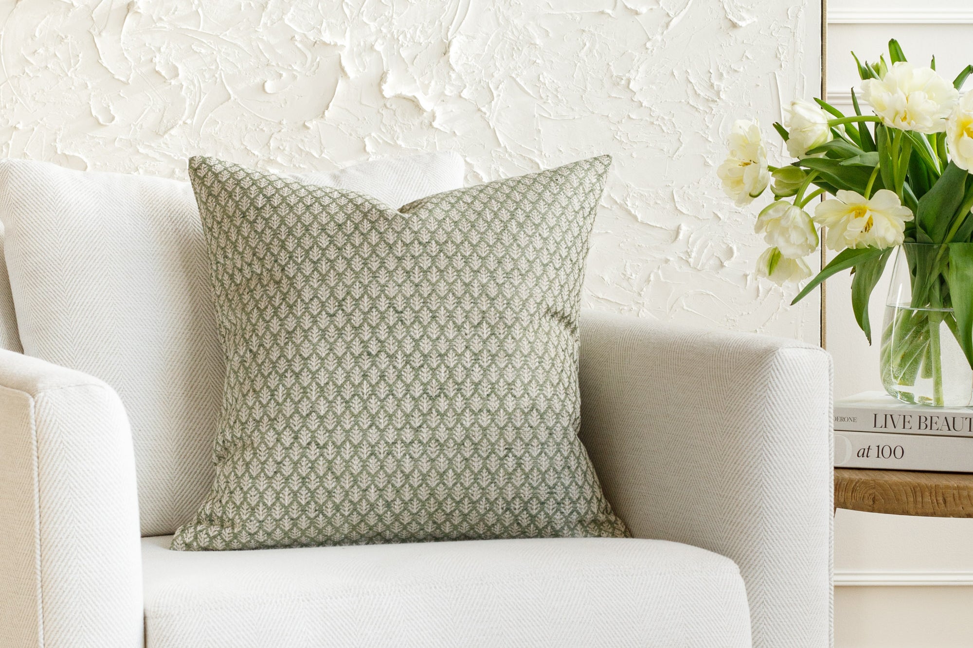 A green and neutral pattern pillow, styled on furniture.