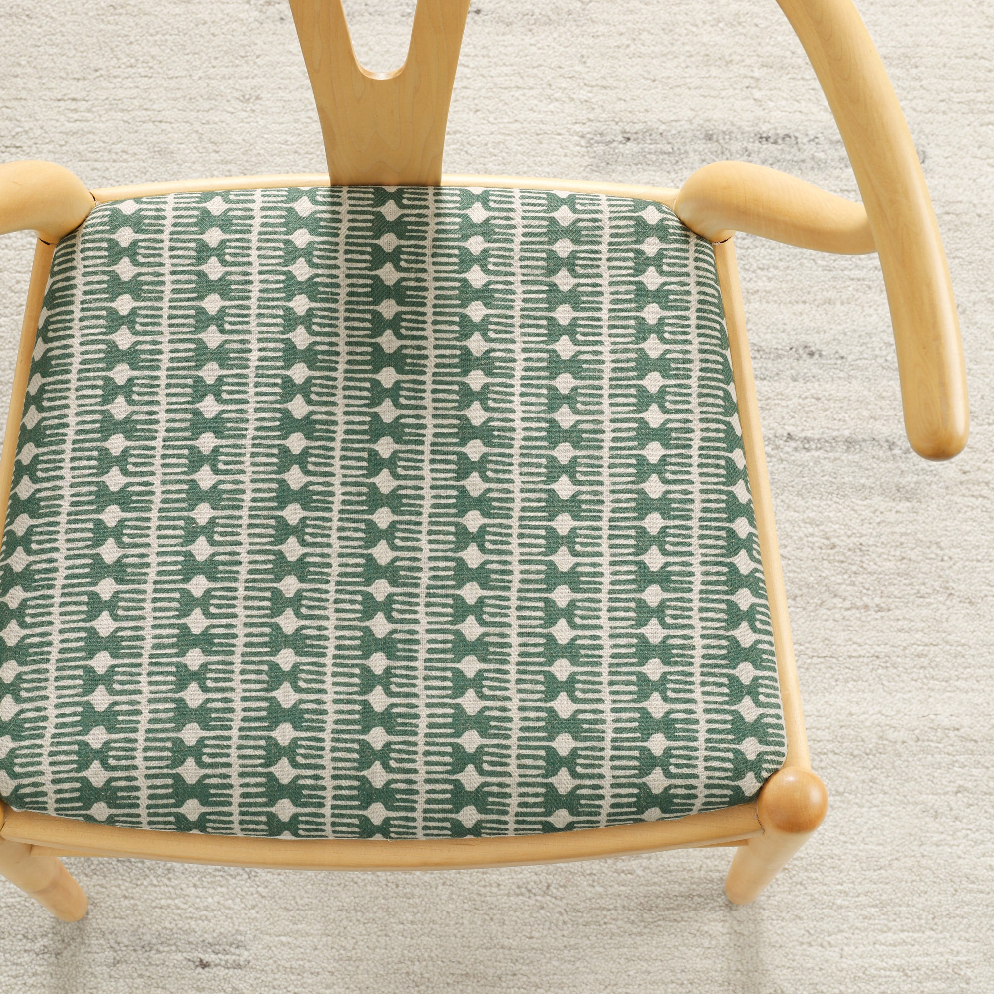 Tonic Living Meadow Emerald upholstery fabric shown on a dining chair seat in a green and white block print.