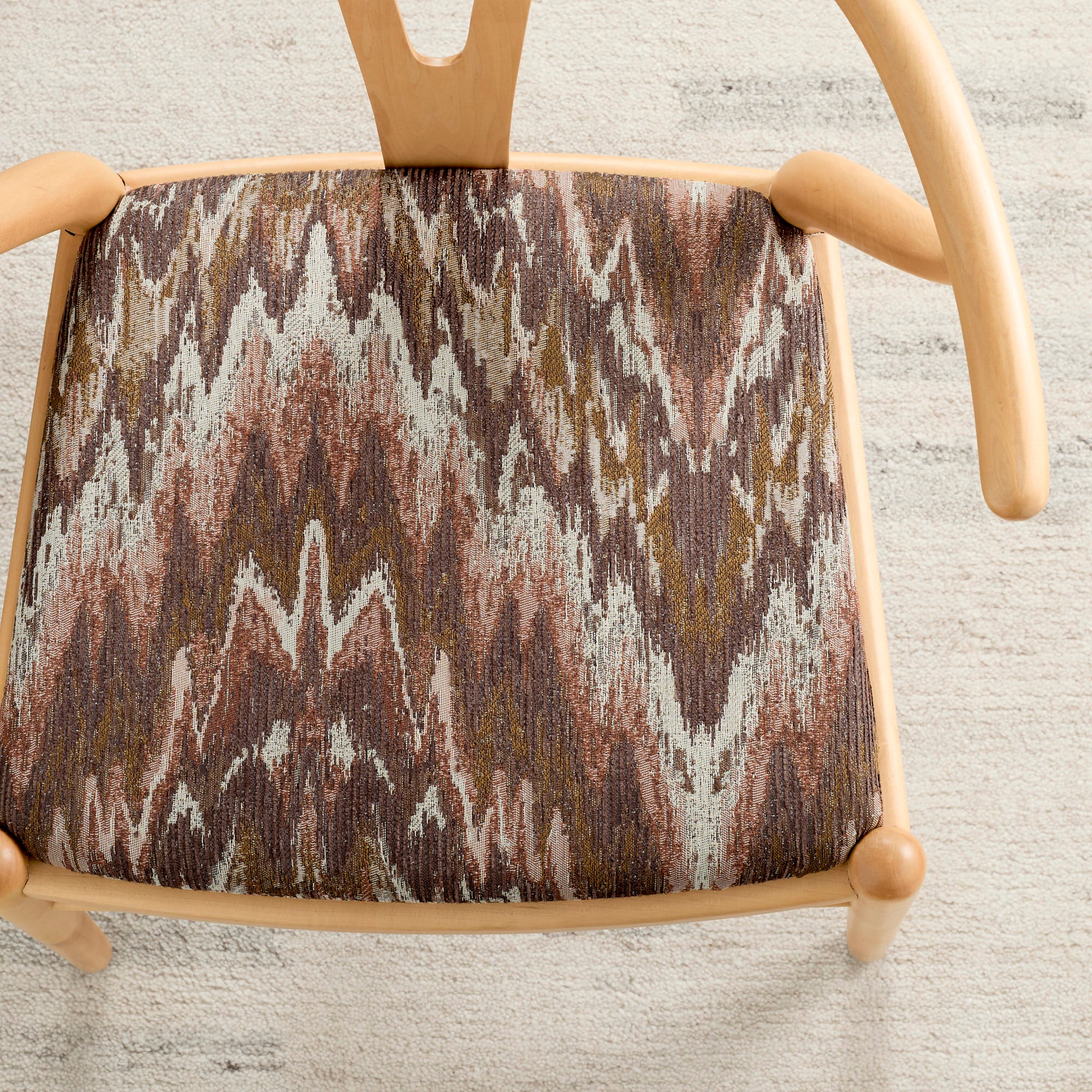 Tonic Living Mendoza Fig upholstery fabric shown on a dining chair in warm multicolour tones.