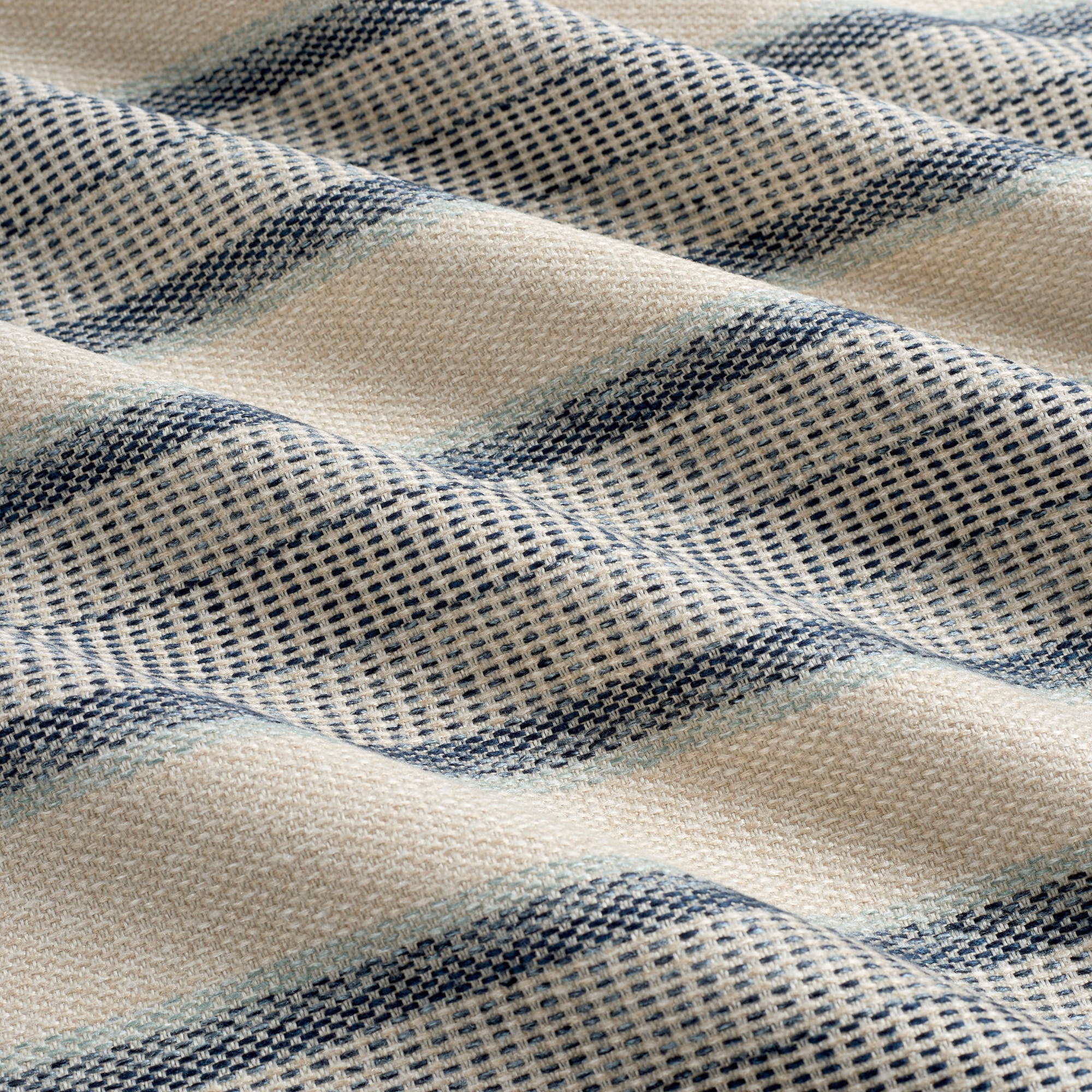 Tonic Living Miller Stripe Denim performance upholstery fabric featuring varied banded stripes in faded denim blue and sandy beige.