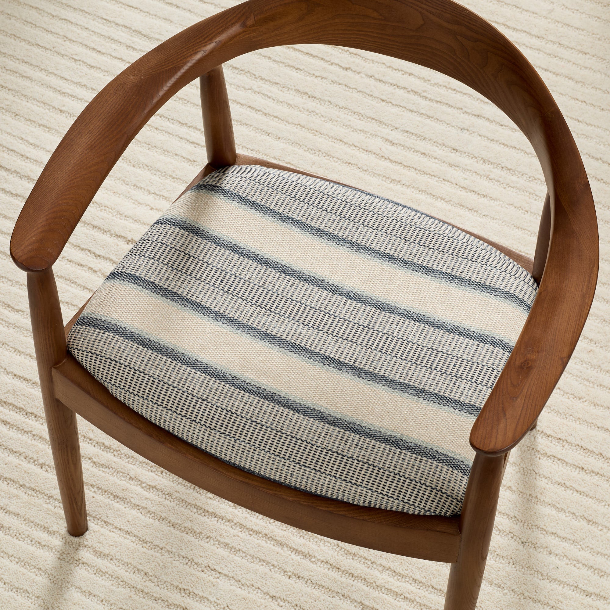 Tonic Living Miller Stripe Denim high-performance fabric shown upholstered on a dining chair seat with soft blue stripes.