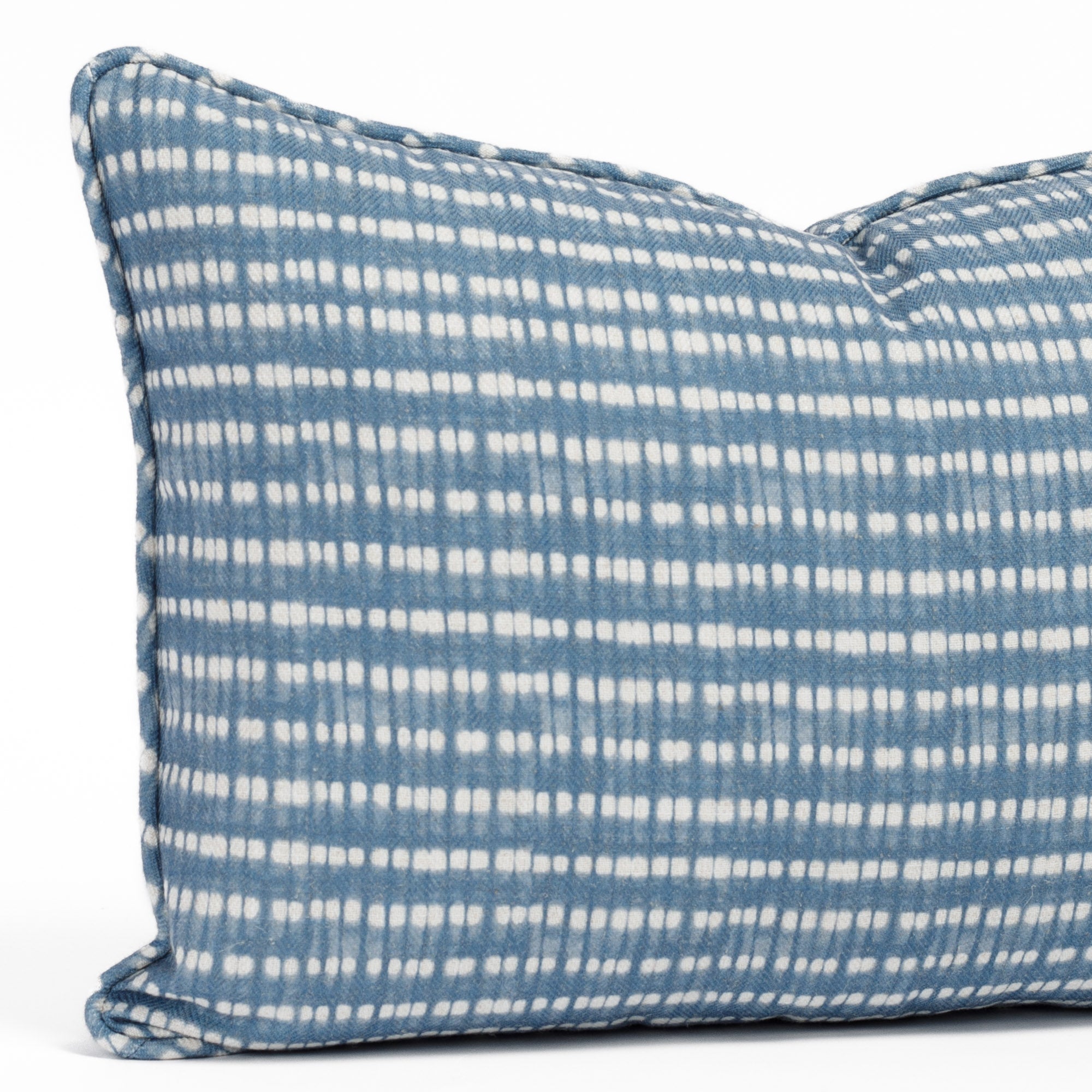 Close-up of a 14x20 blue and white lumbar pillow with a dotted stripe pattern and piping detail (Nile Indigo by Tonic Living).