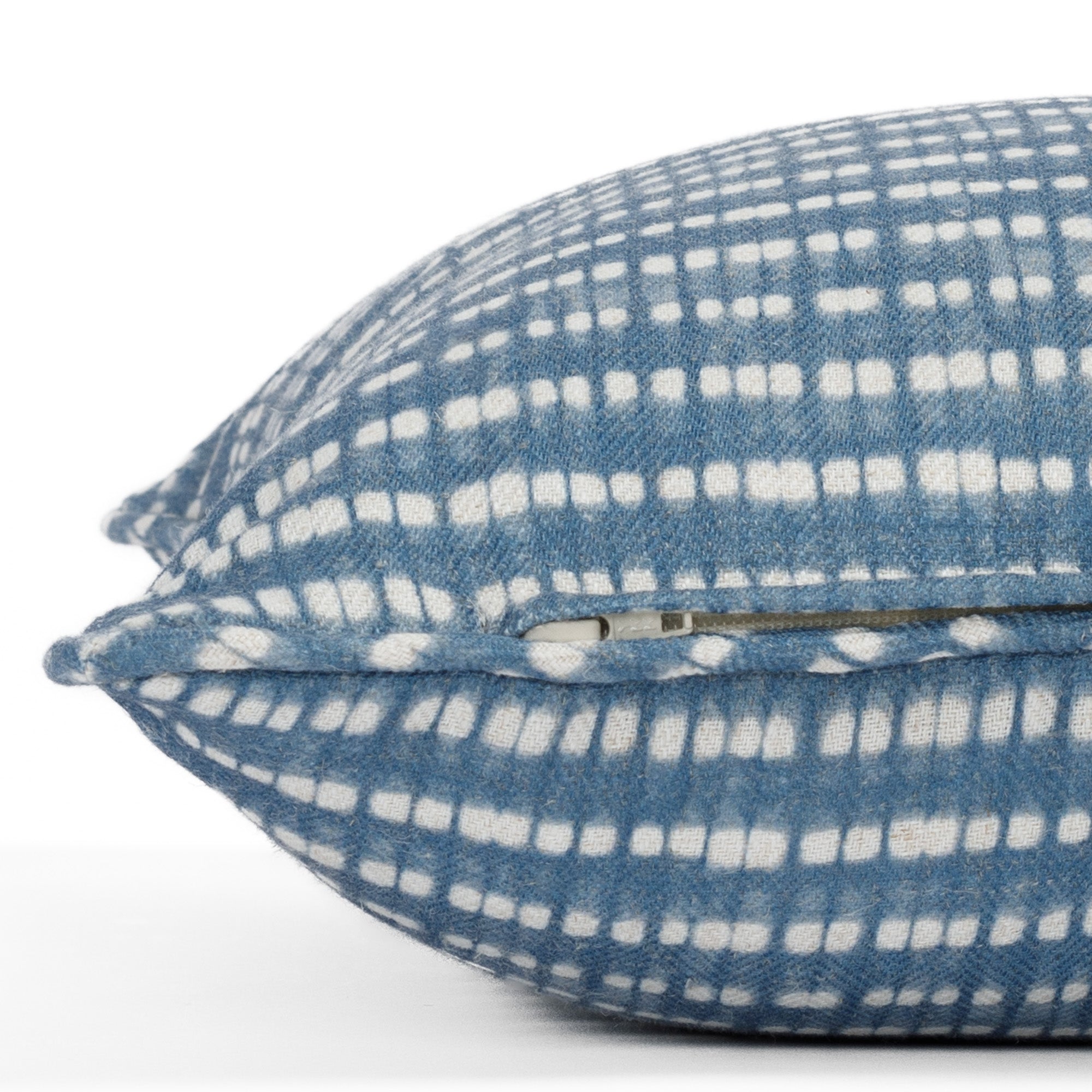 Close-up zipper side view of a denim blue and white pillow with piped detail and dotted stripe pattern (Nile Indigo from Tonic Living).