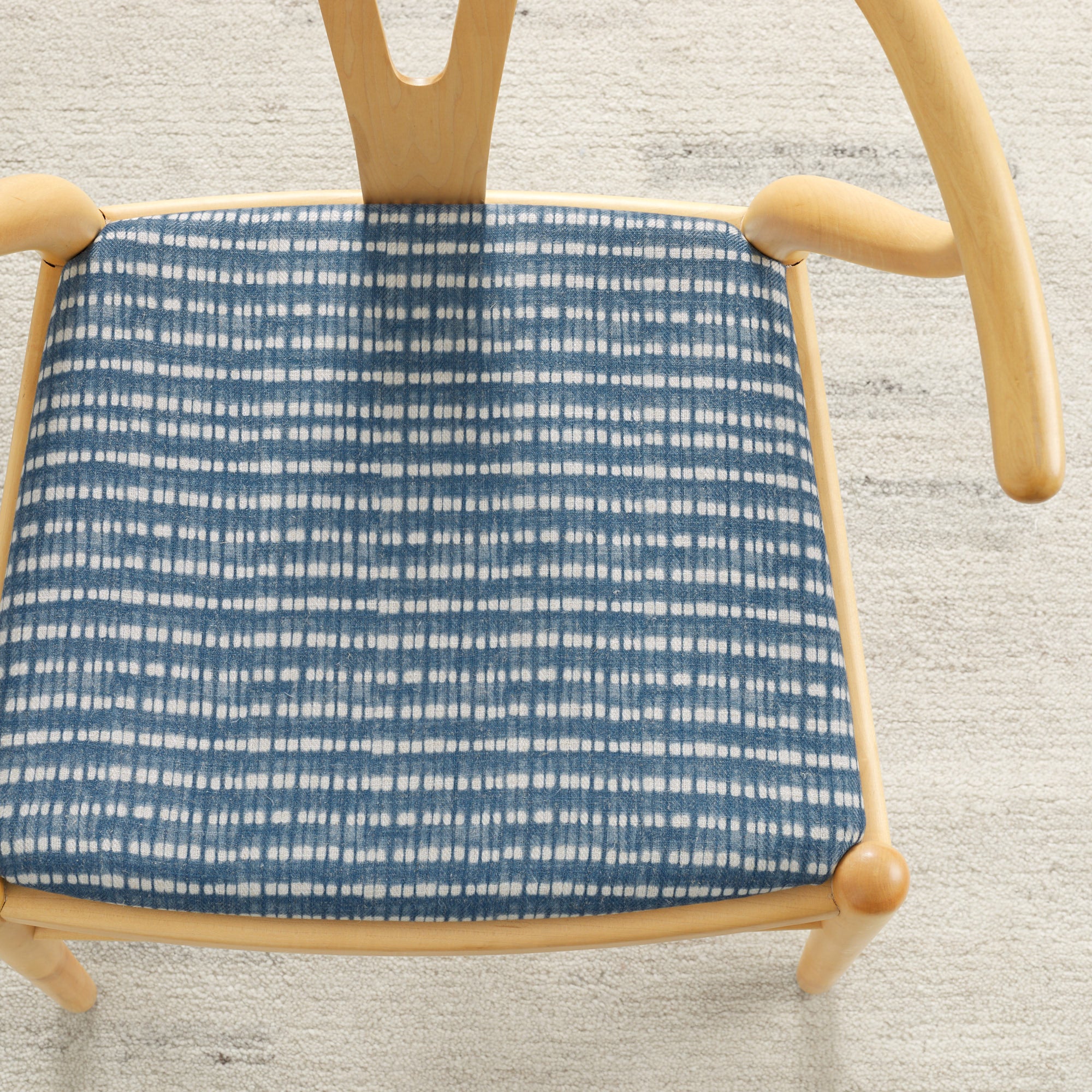 Tonic Living Nile Indigo upholstery fabric shown on a dining chair seat in a blue and white tie-dye stripe.