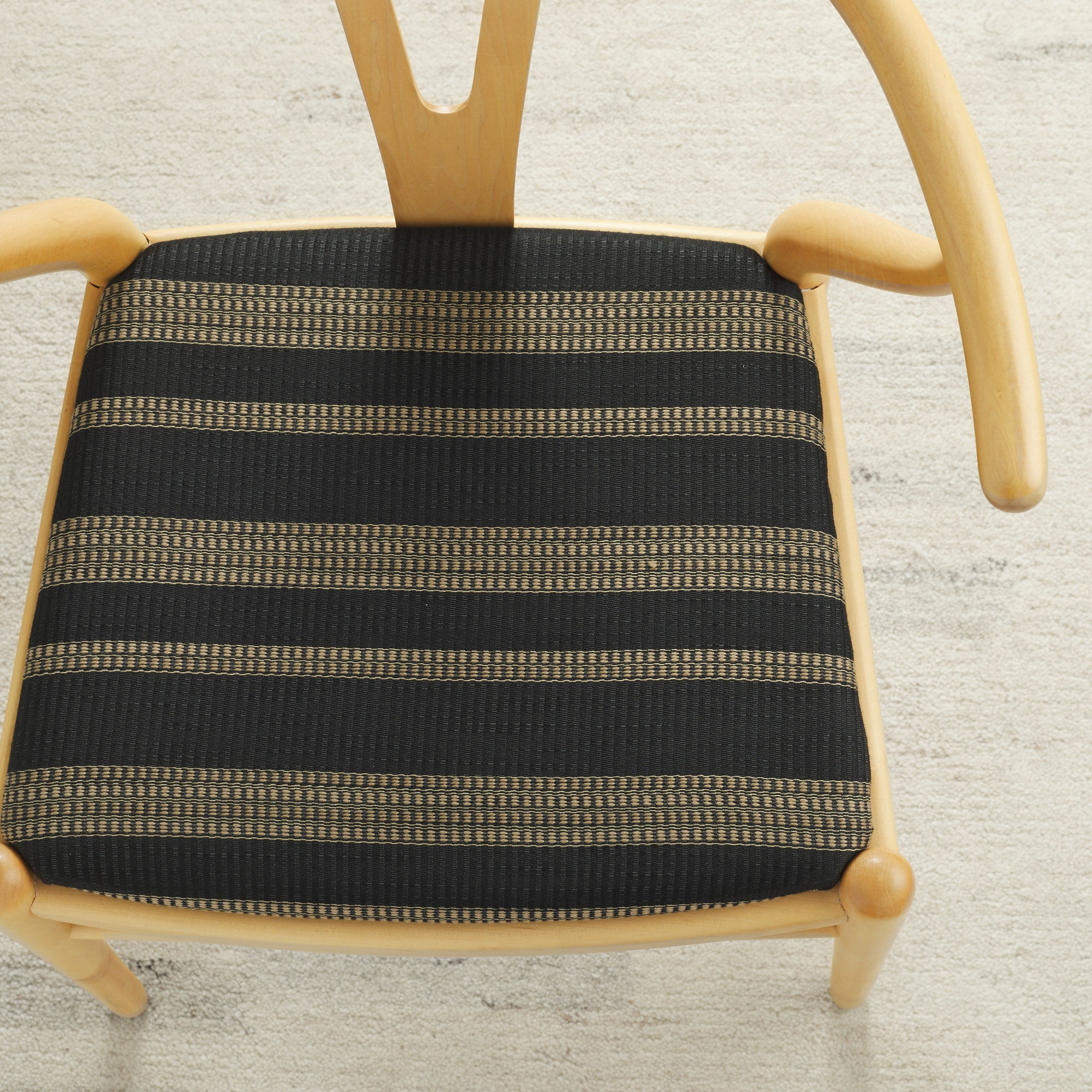 Tonic Living Odessa InsideOut Carbon indoor/outdoor upholstery fabric on a dining chair seat in black and tan stripe.