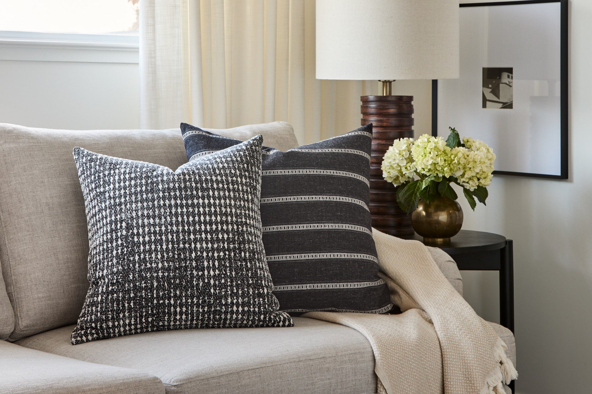 A pair of black & white graphic cushions from Tonic Living, styled on a sofa.