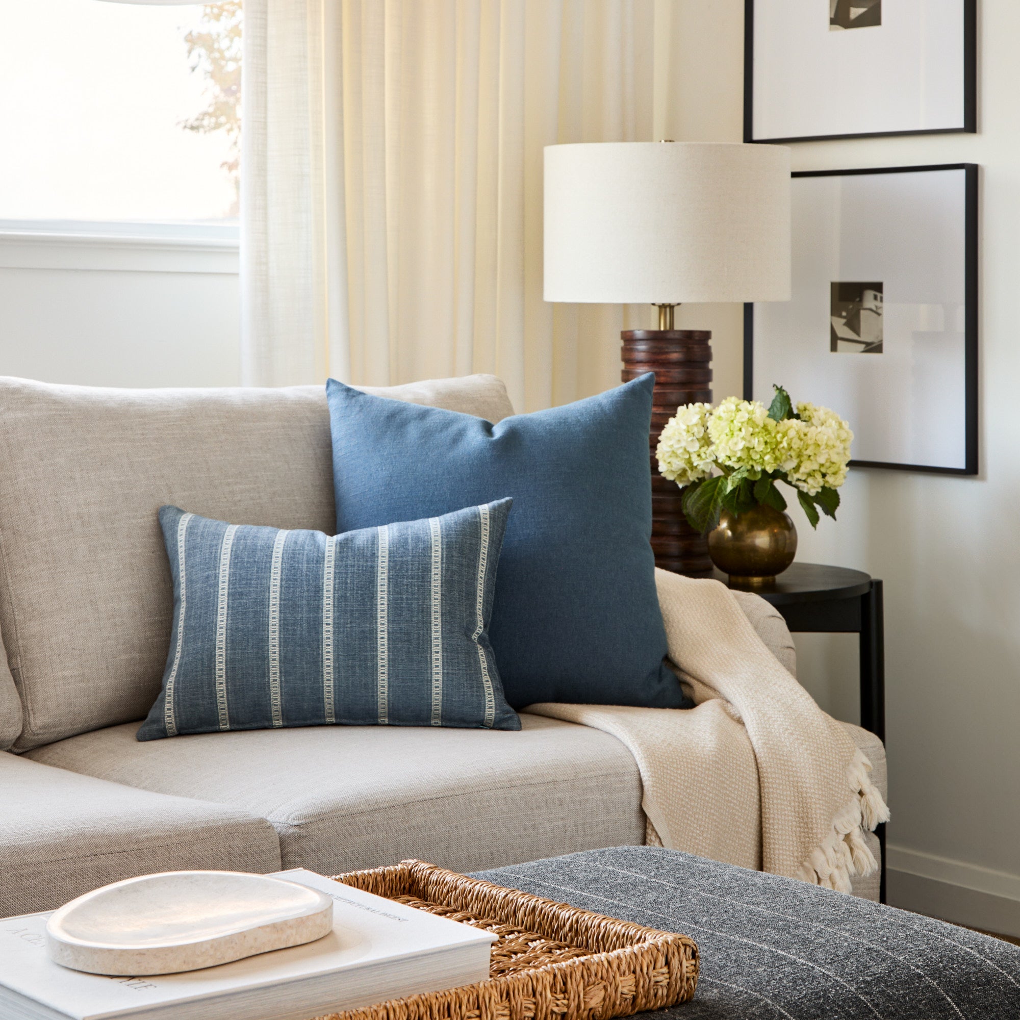 Tonic Living Brunswick Stripe blue striped lumbar cushion styled on a sofa beside a solid blue throw pillow.