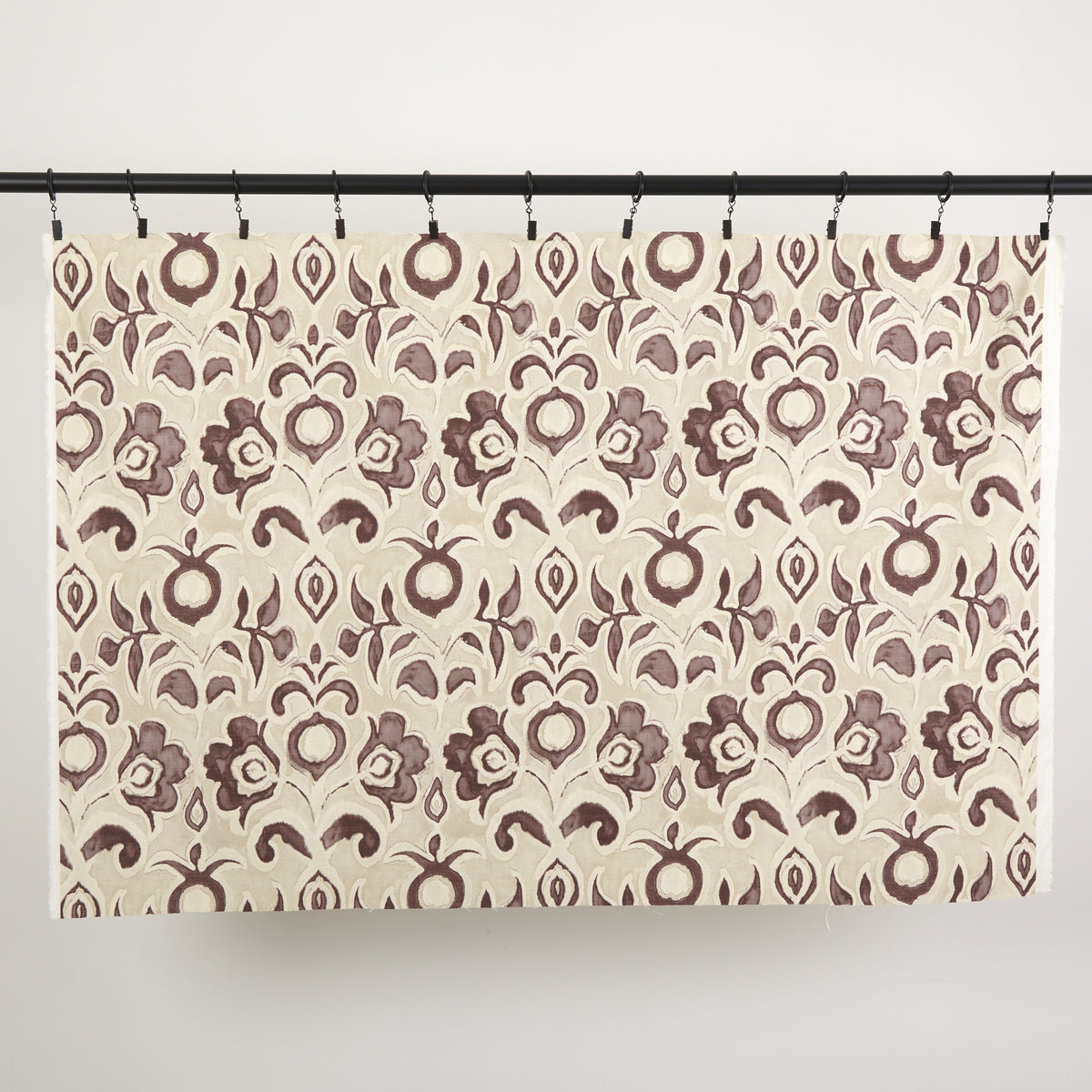 Full yard of Tonic Living Paloma Fabric in Mauve hanging to show the scale and drape of its muted purple floral pattern.
