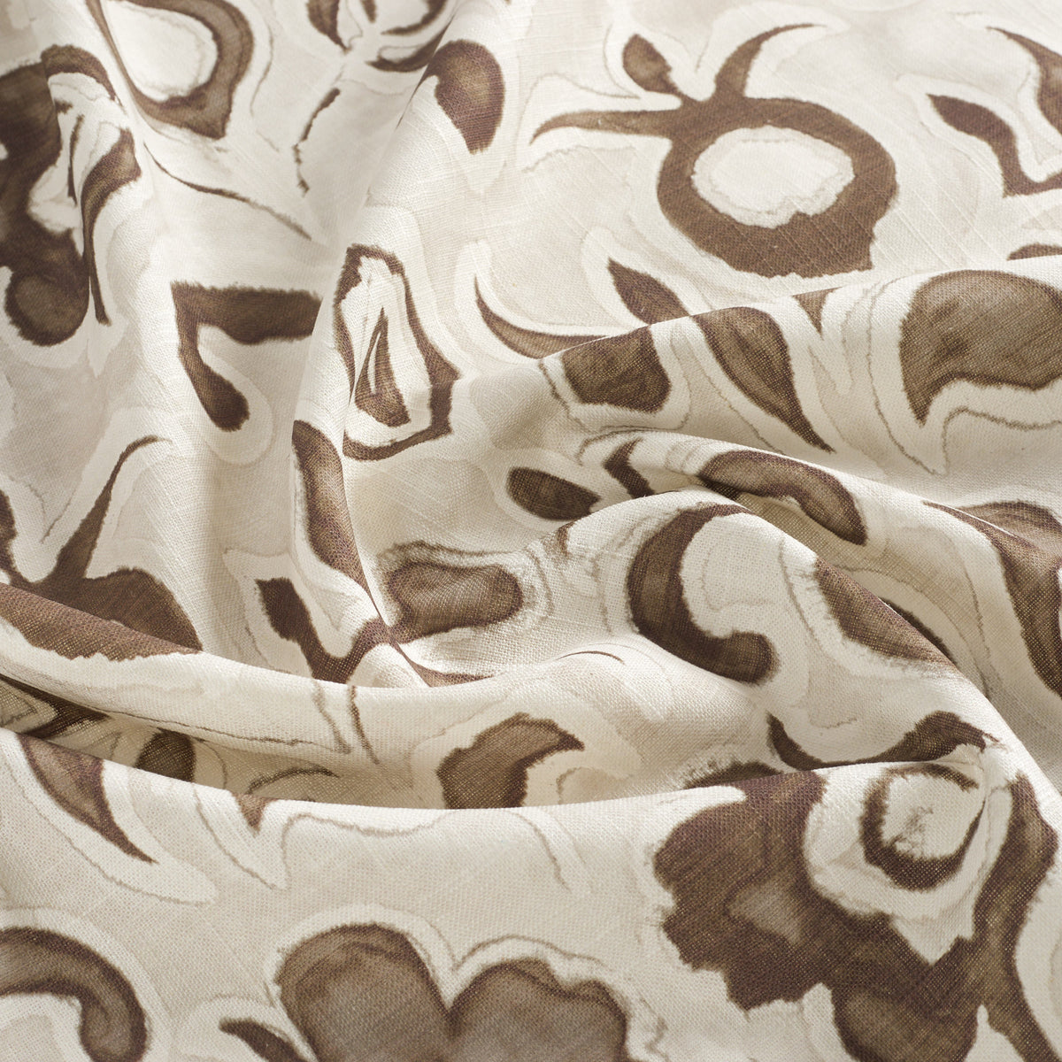 Close up of Tonic Living Paloma Walnut drapery fabric showing stylized coffee brown flowers and scrolling leaves with a watercolour effect.