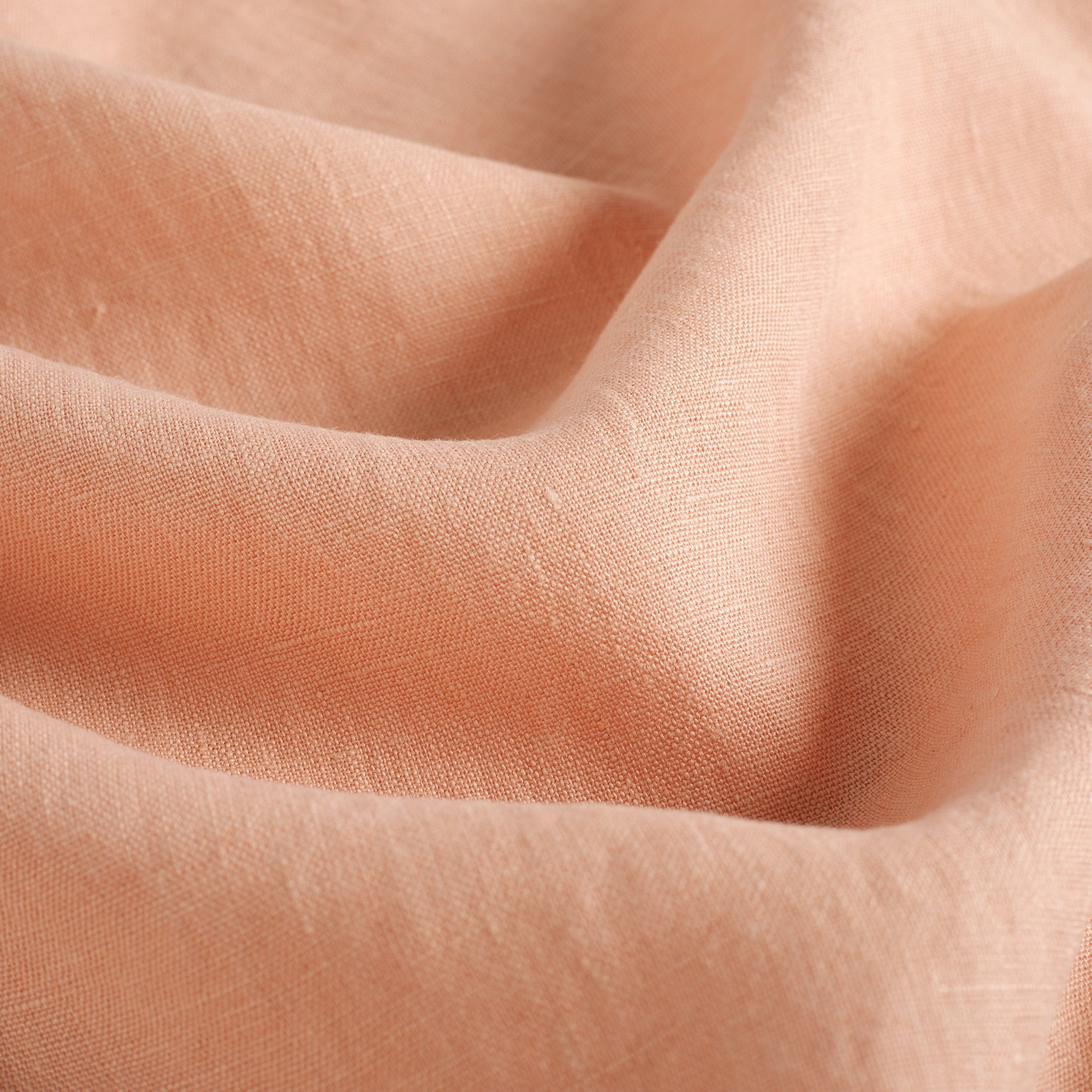 Close up of Tonic Living Pietra Salmon Pink fabric showing soft salmon linen weave and natural slub texture.