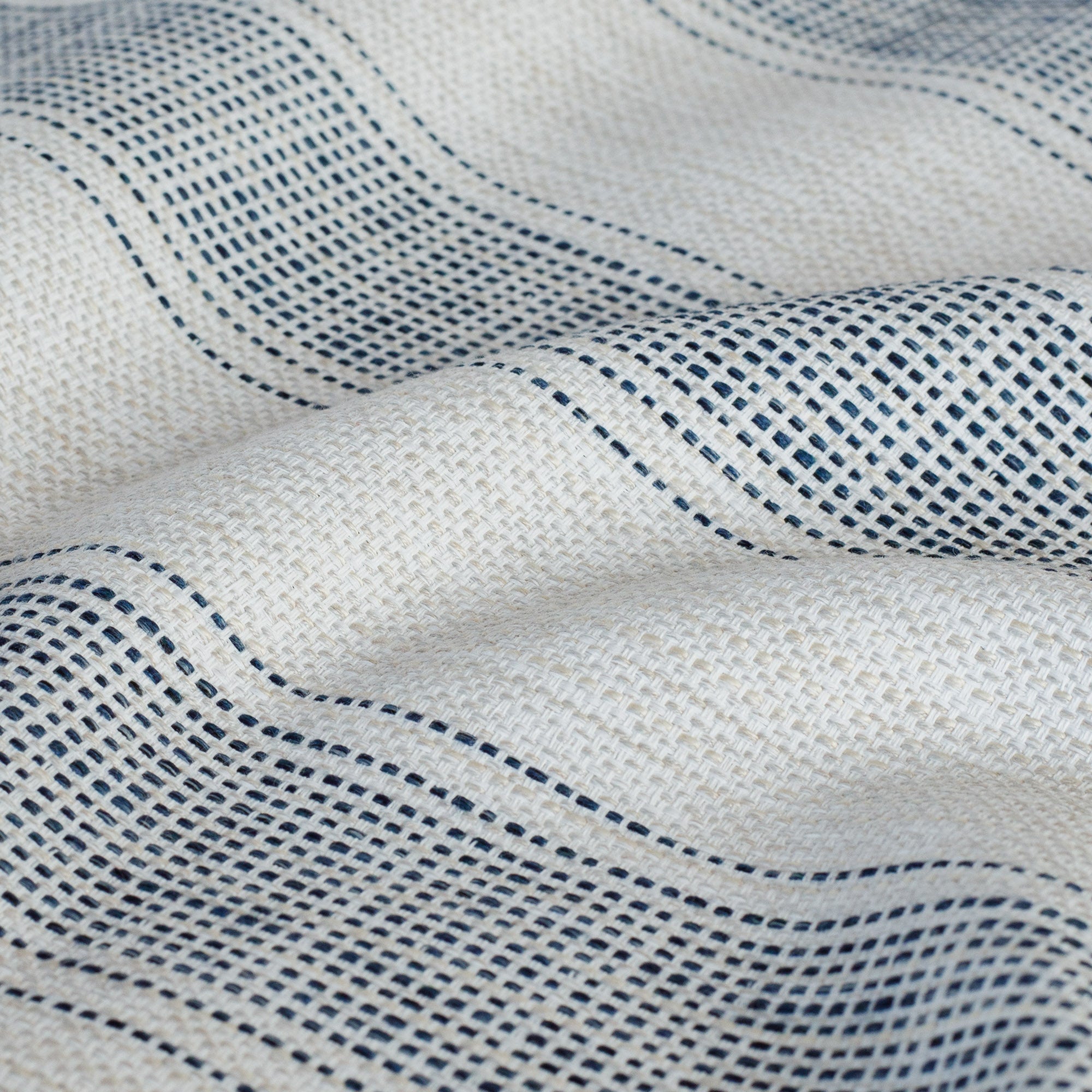 Revitalize Denim, a beige and navy blue striped outdoor fabric with dotted pattern from Tonic Living: close-up view.