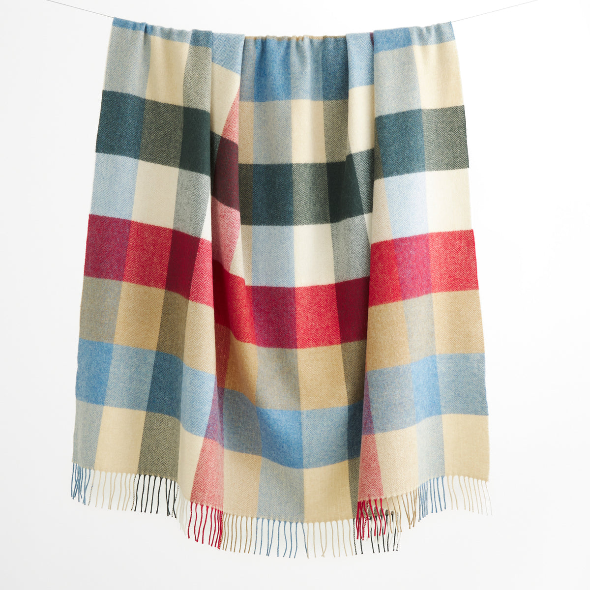 Tonic Living Rowan Check Wool Throw Blanket in Orchard, a colourful wool blanket with an oversized blue, red, green, and neutral check.