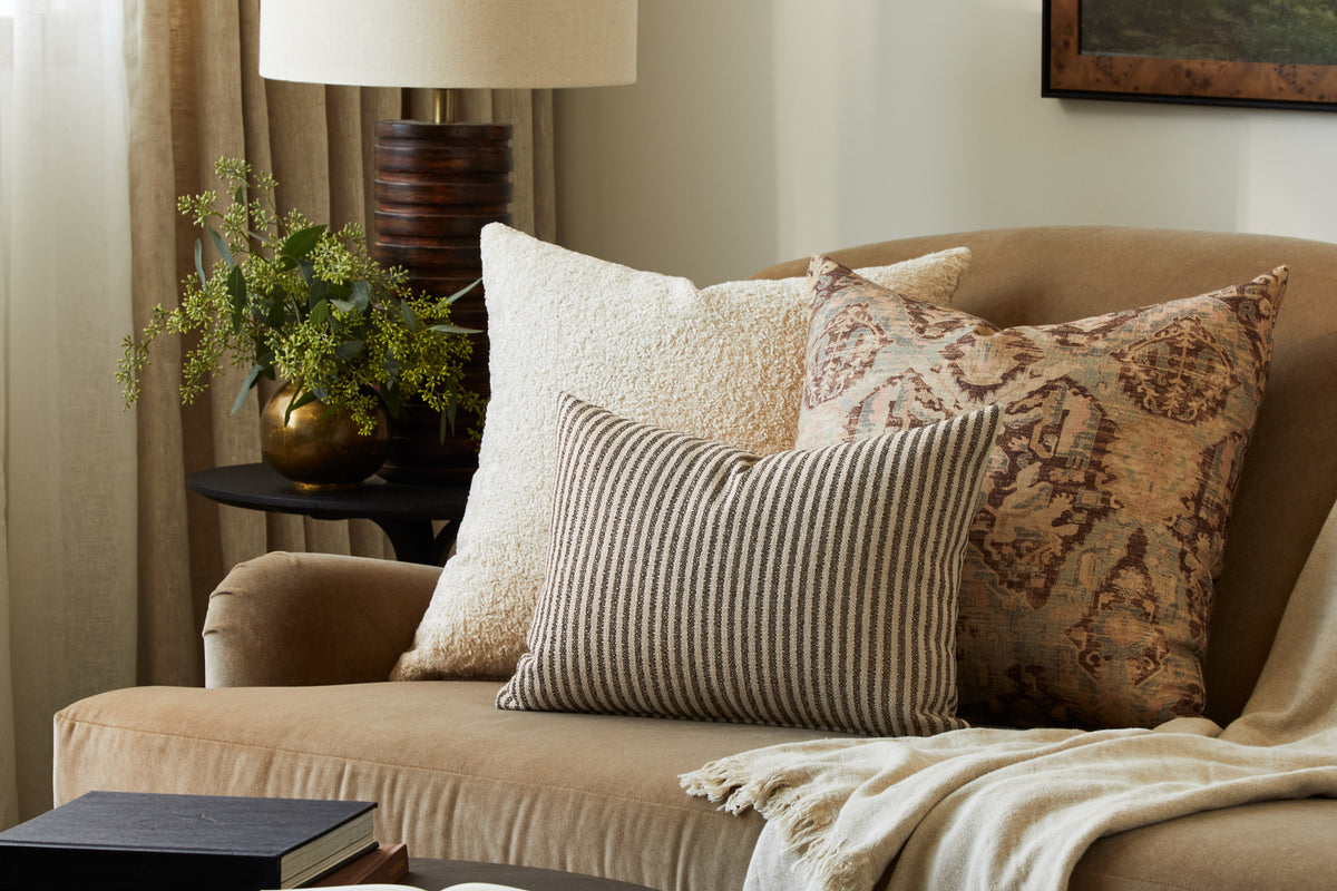 Tonic Living Crosby Stripe Truffle lumbar cushion styled on a brown velvet sofa with neutral textured and patterned throw pillows.
