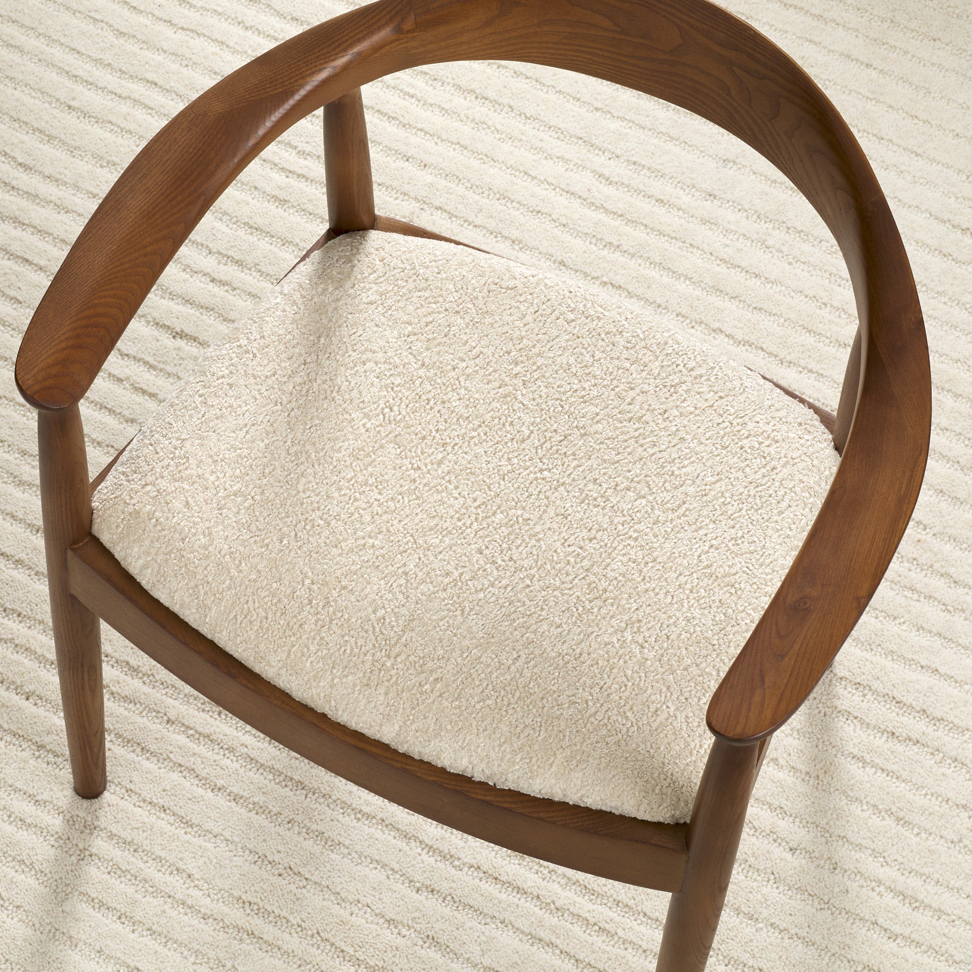 Tonic Living Rupert Parchment cream bouclé upholstery fabric shown on a dining chair seat.