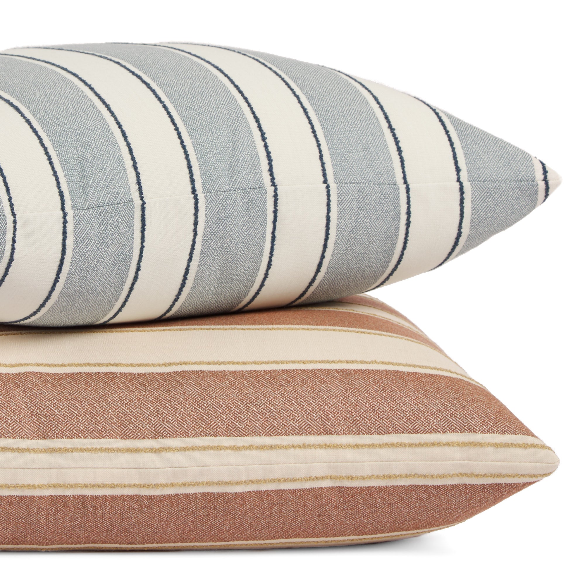 Stack of Tonic Living Sentiment 20x20 outdoor pillows in terracotta and denim blue featuring bold stripe designs.
