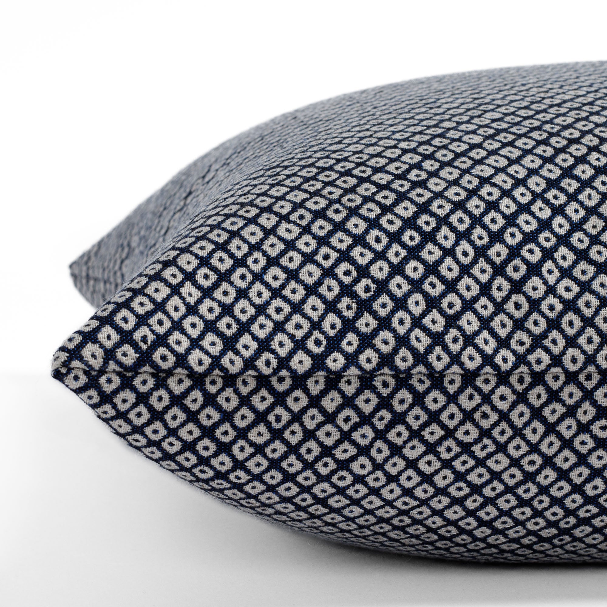 Shibori Indigo, a dark blue and white dotted pattern indoor/outdoor pillow from Tonic Living: close-up side view.
