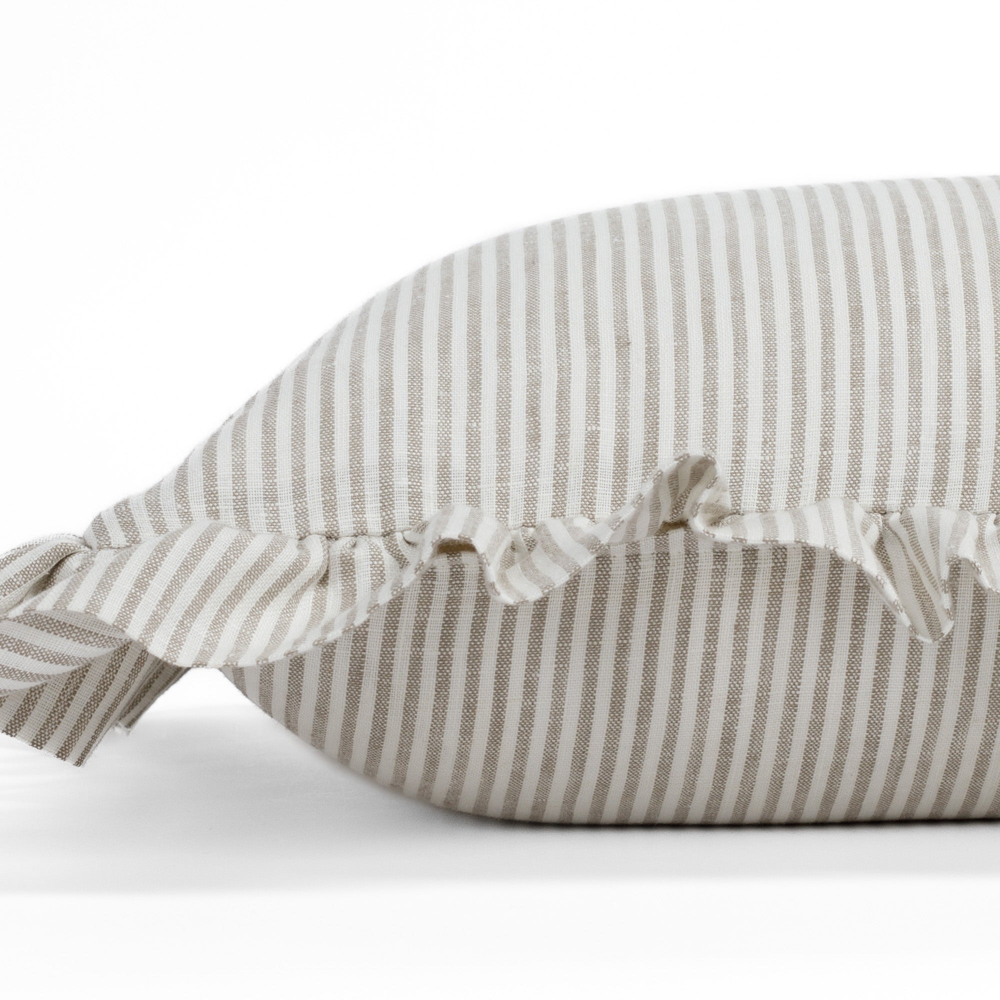 Side close-up of the Siena 14x20 ruffle lumbar pillow from Tonic Living, showcasing the soft edge ruffle and subtle beige stripes in a natural, earthy tone.
