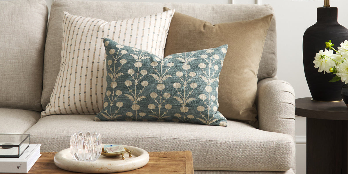 Tonic Living Hazel Pool botanical lumbar cushion styled on a sofa with a neutral striped pillow and warm brown velvet pillow.
