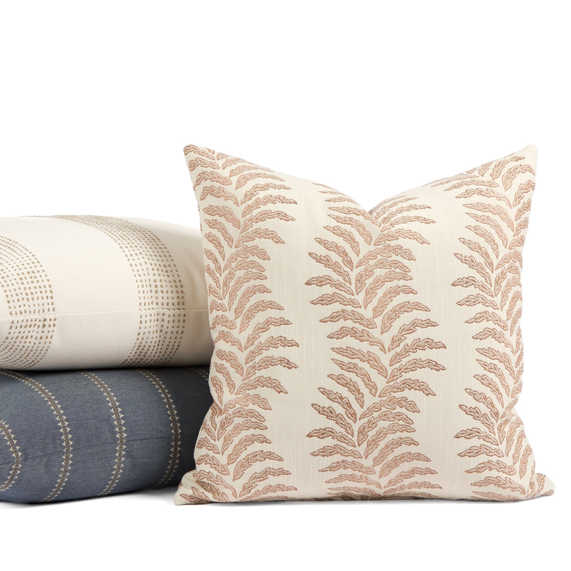 Tonic Living Swoon Terracotta outdoor cushion styled in front of cream and blue throw pillows.