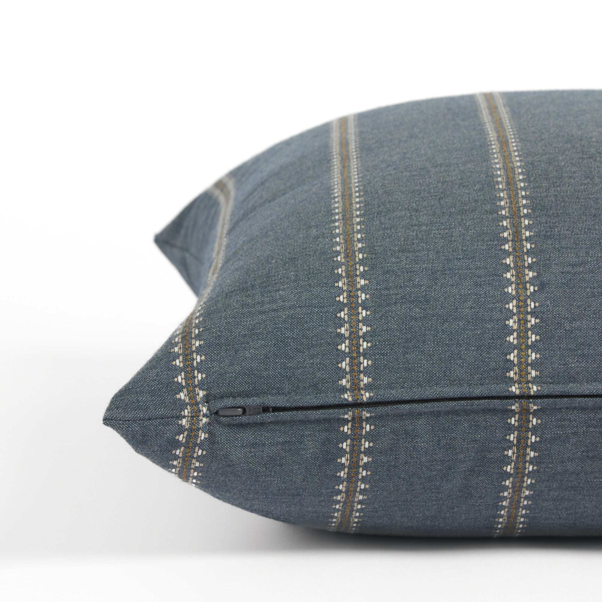 Side zipper detail of Tonic Living Talisman 22x22 outdoor toss pillow in dark blue with an embroidered stripe.