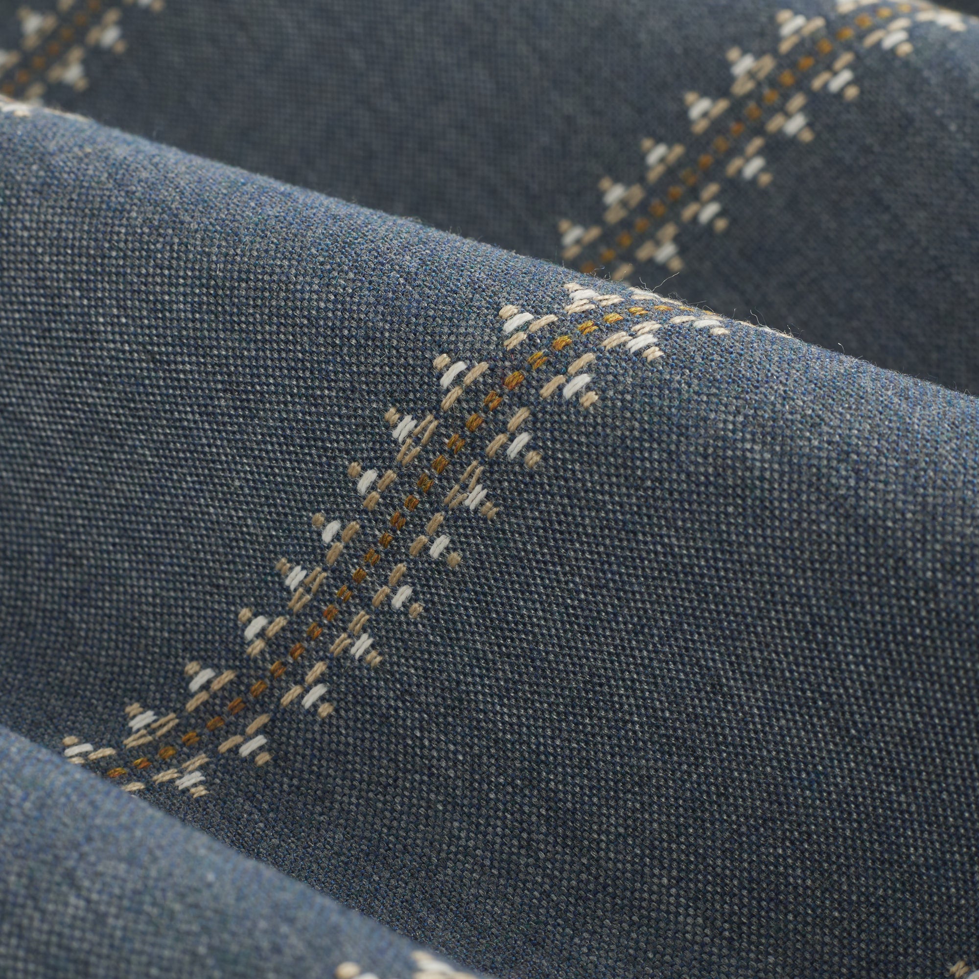 Close up of Tonic Living Talisman Sunbrella Denim blue fabric showing raised stitch detail in a multicolour geometric stripe.