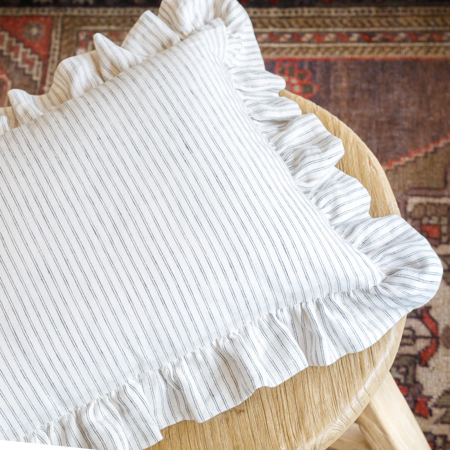 Verona Stripe 14x20 Jet ruffled pillow styled atop a stool, showing its casual elegance and soft structure—perfect for cottagecore or vintage-style interiors.