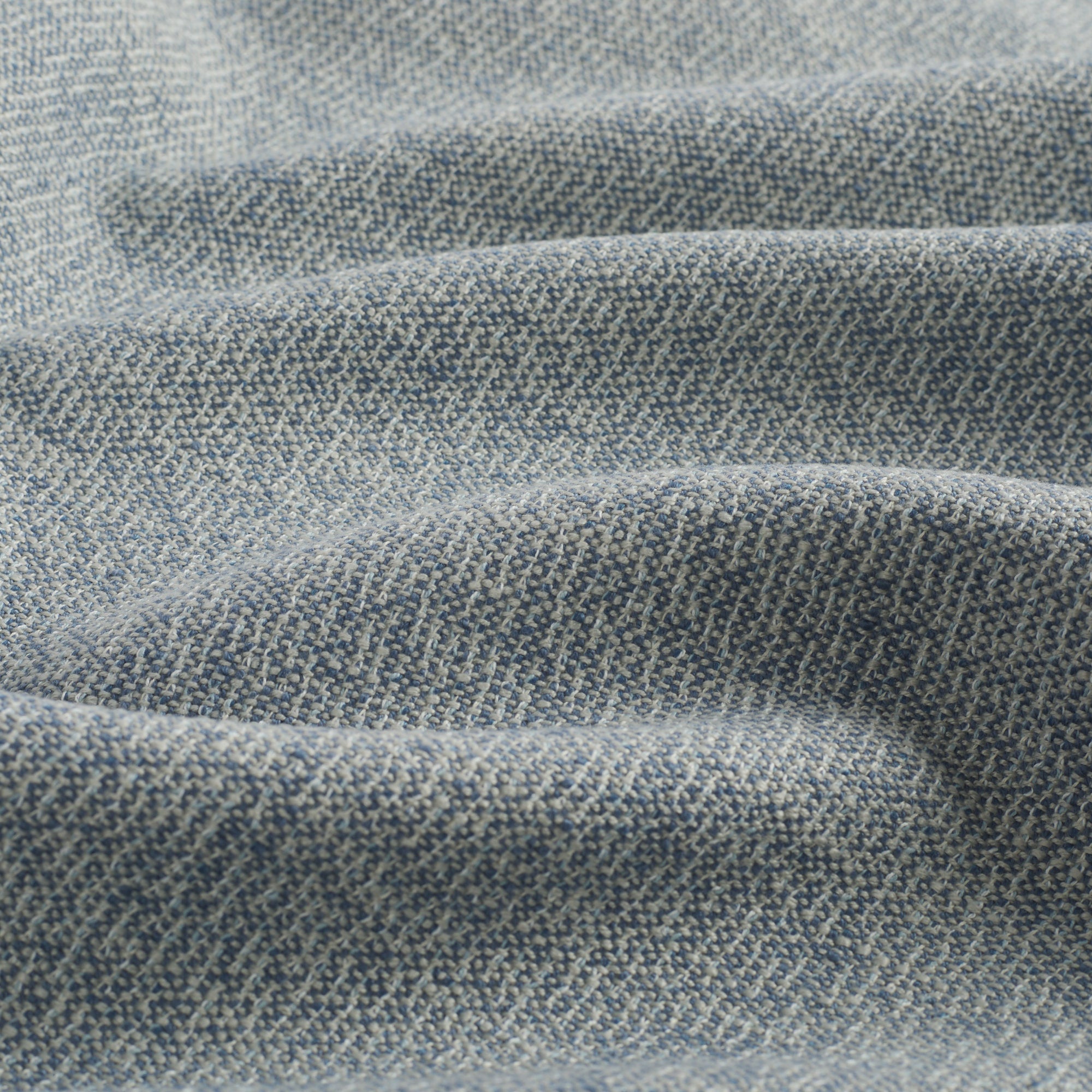 Close up of Tonic Living Troy InsideOut Denim upholstery fabric highlighting its solid blue textured, linen-inspired weave.