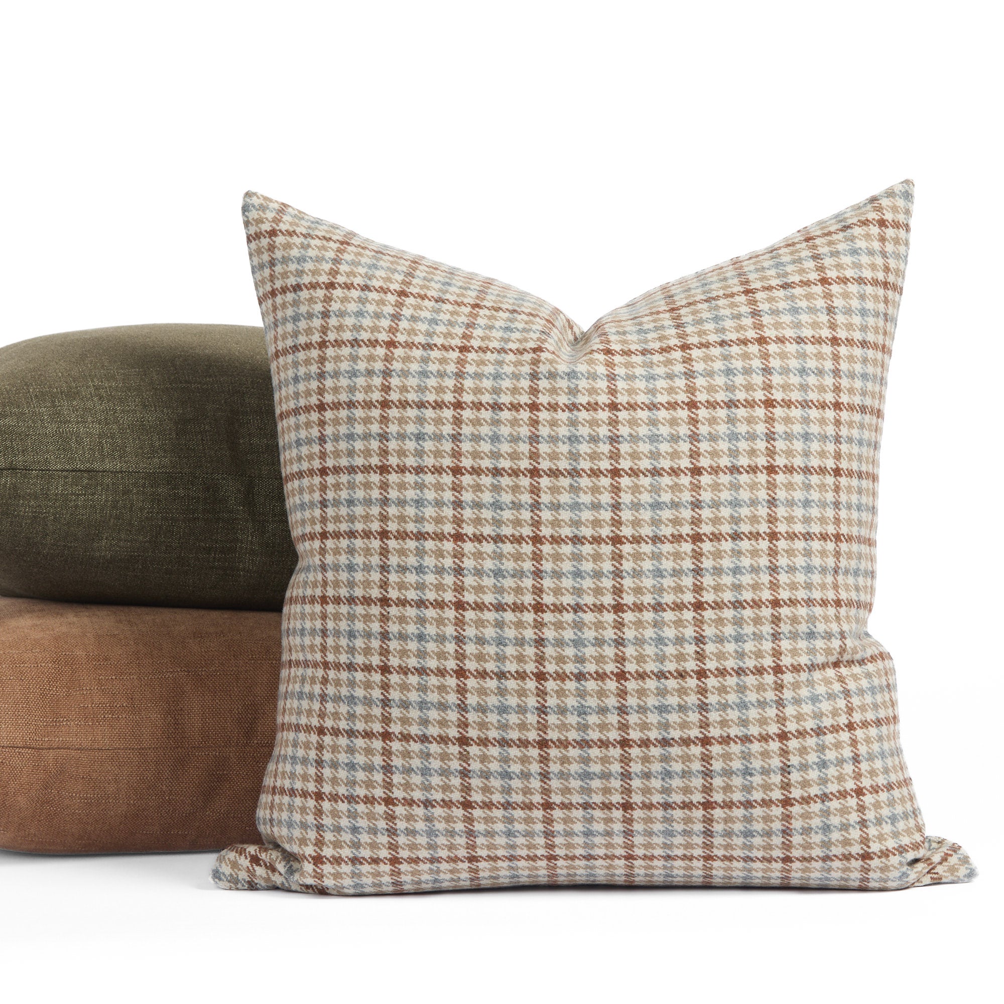 Vesper Plaid 20x20 houndstooth check cushion in beige, blue, and rust, shown with green and brown pillows.