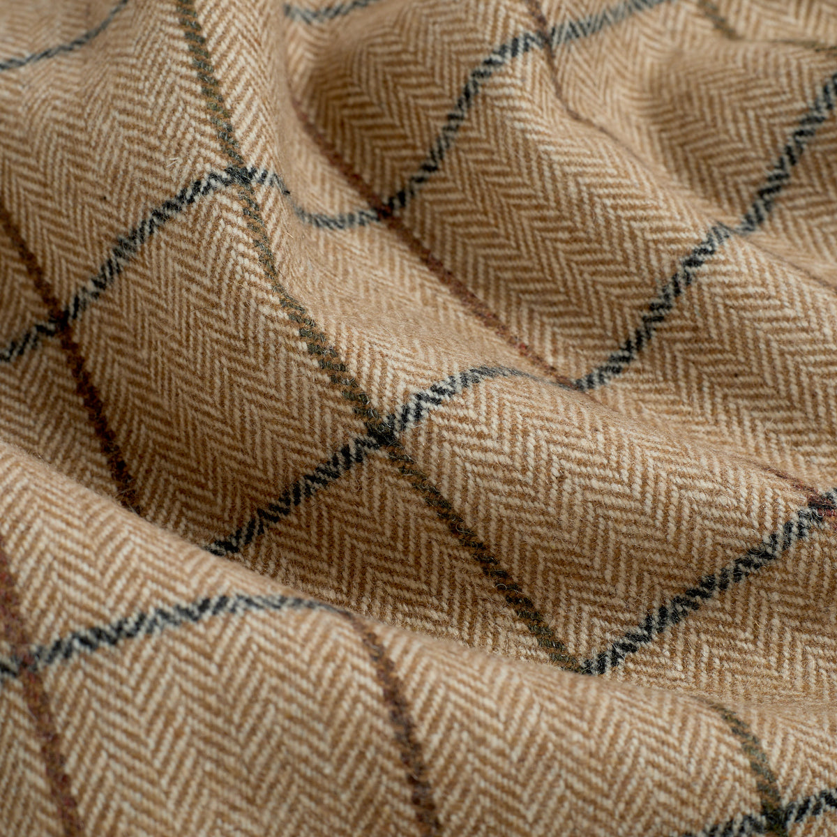 Close up of Tonic Living Walker Plaid Camel fabric showing a fine herringbone weave and windowpane check in camel, brown, and navy.