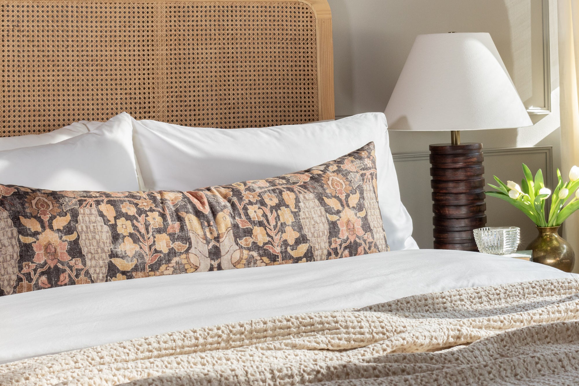 a cozy pillow with a beautiful botanical print in warm earthy colours on a queen bed