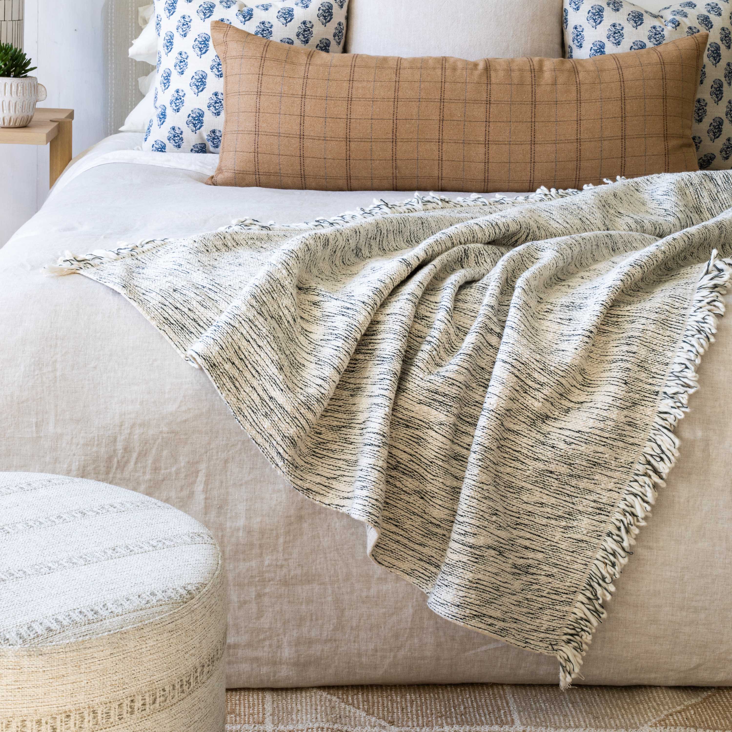 Silvero Pepper cream and black marled cotton blanket on a bed