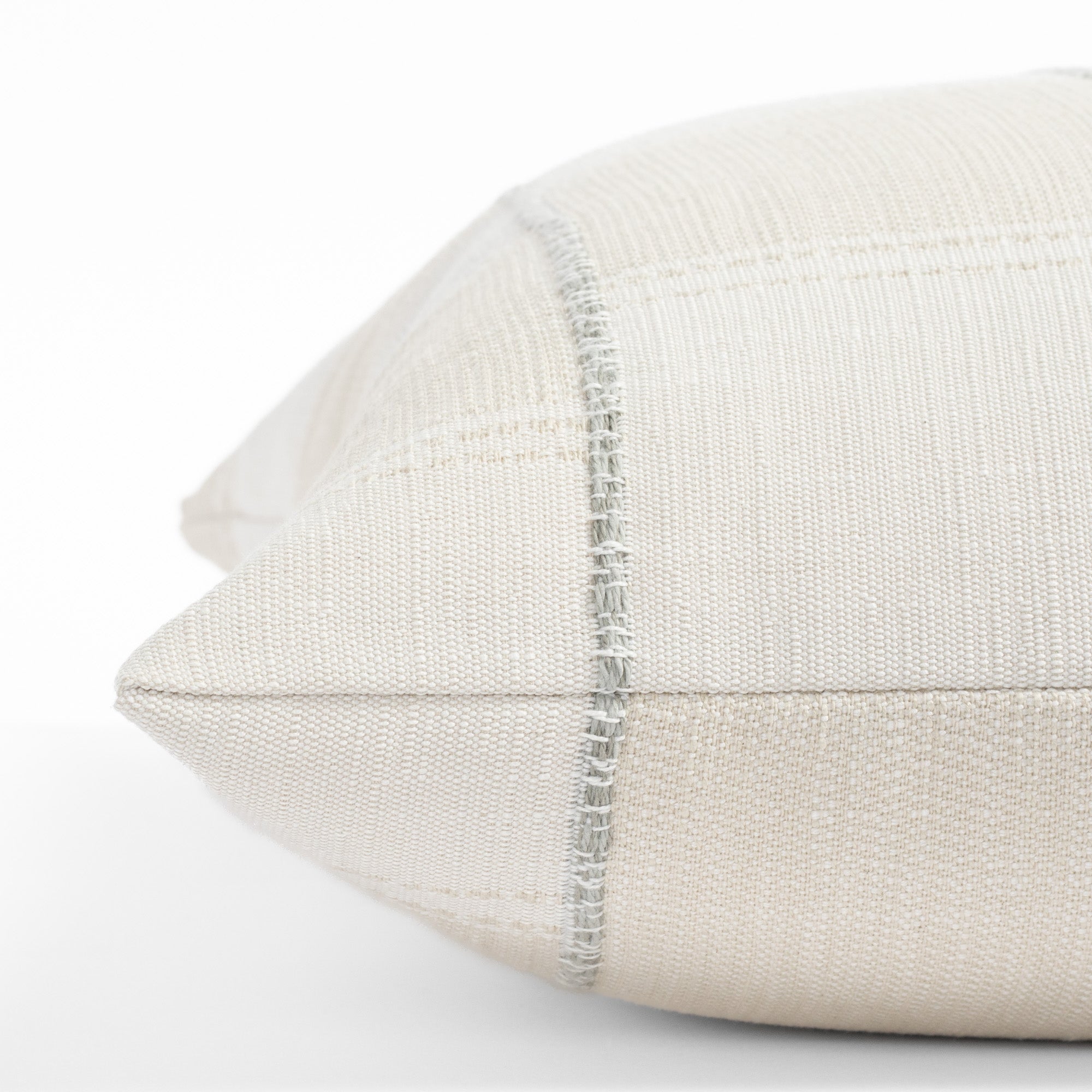 a chunky light blue stripe and white cream patchwork patterned throw pillow : close up side view