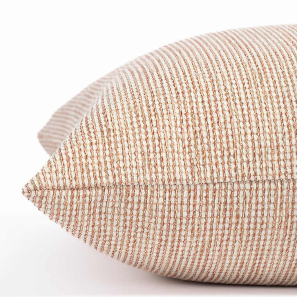 a terracotta pink and taupe tweedy textured outdoor pillow : close up side view